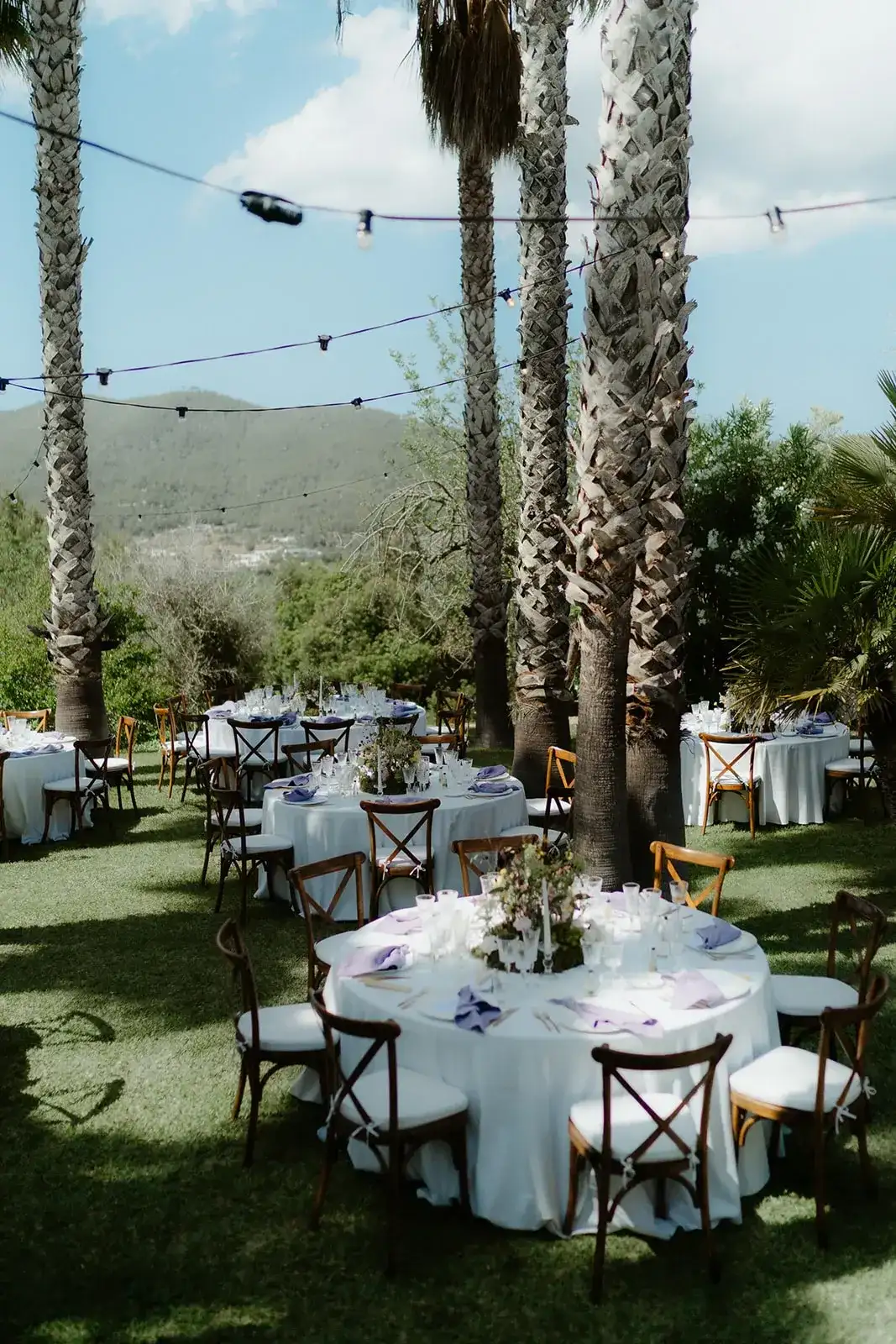 Round tables under palms and festoon lights, Can CG
