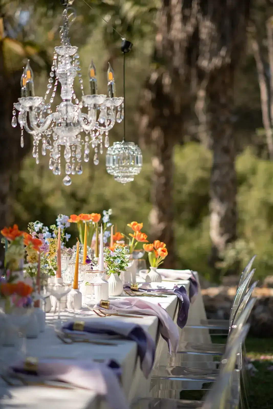 A chandelier and orange flowers over a garden table