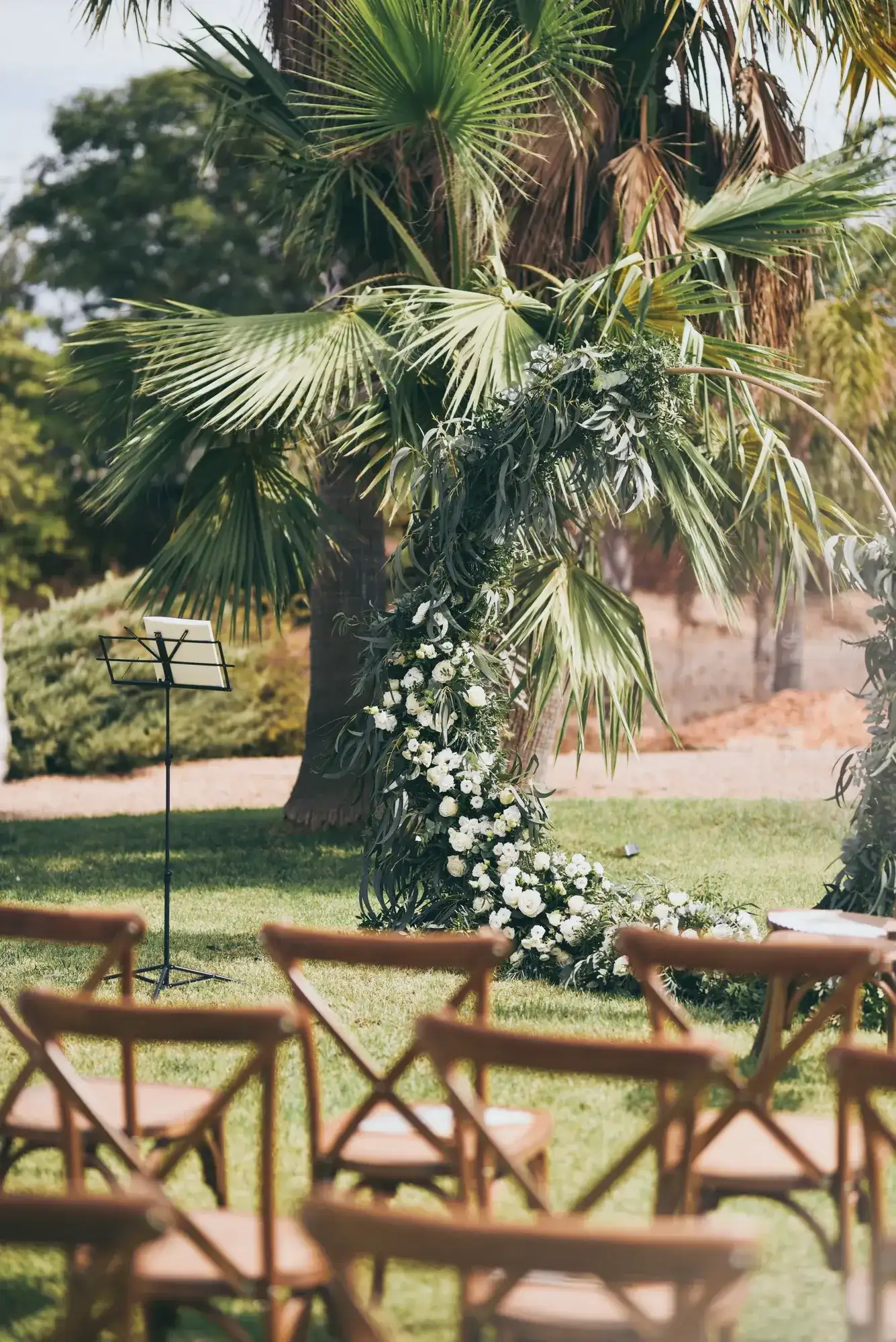 A palm-and-flower arch over the ceremony chairs