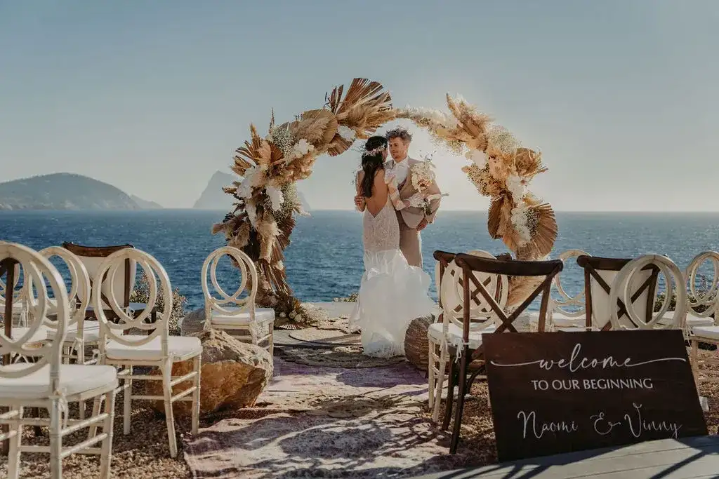 Bride and groom under the pampas arch, the sea behind, 7Pines Ibiza