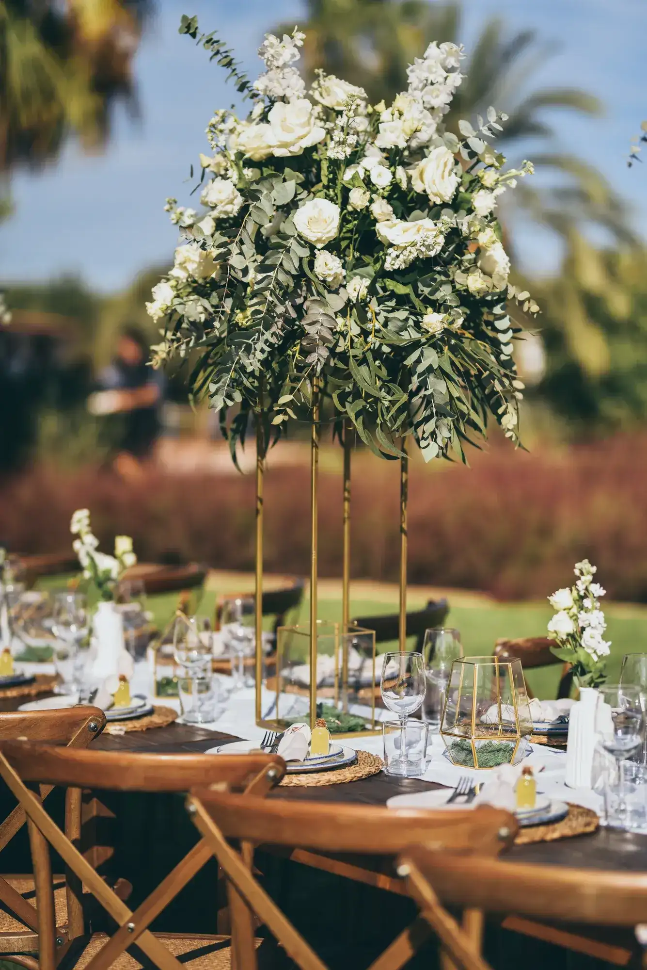 A tall white flower tower over a wooden table