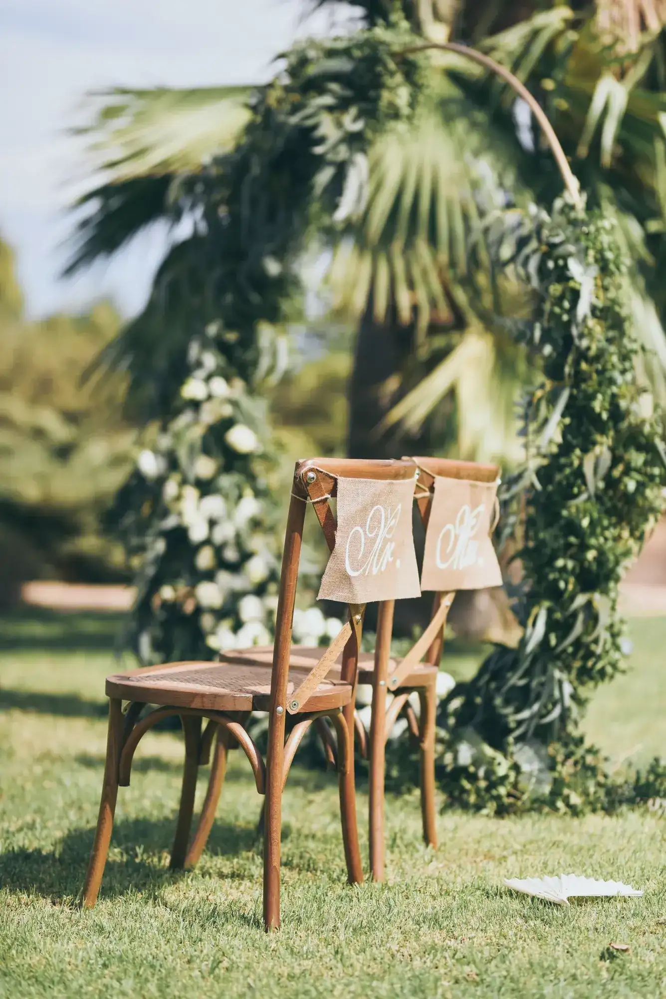 A green hoop arch and cross-back chairs on the lawn