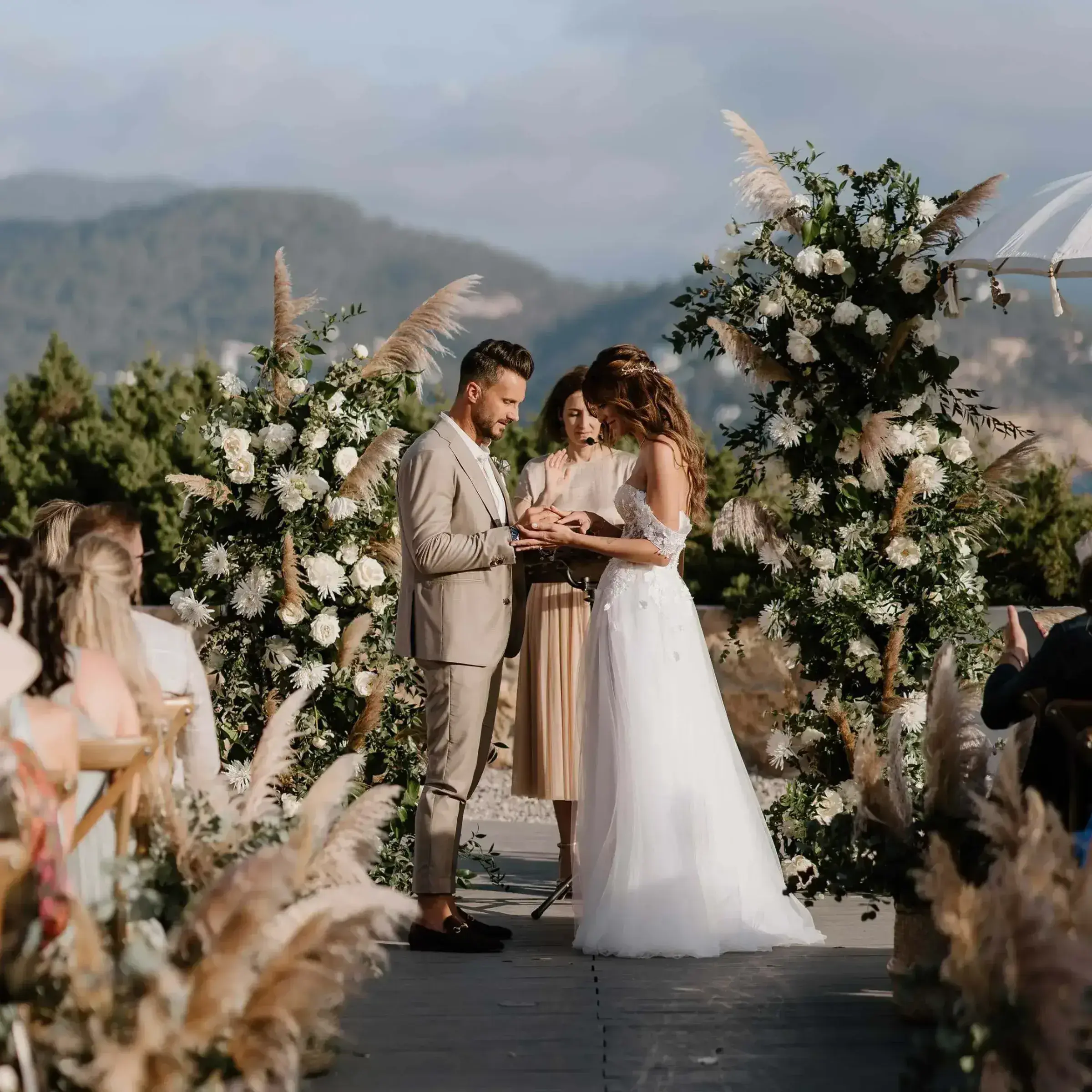 7Pines Resort Ibiza: Couple exchanging vows between floral pillars with hills behind