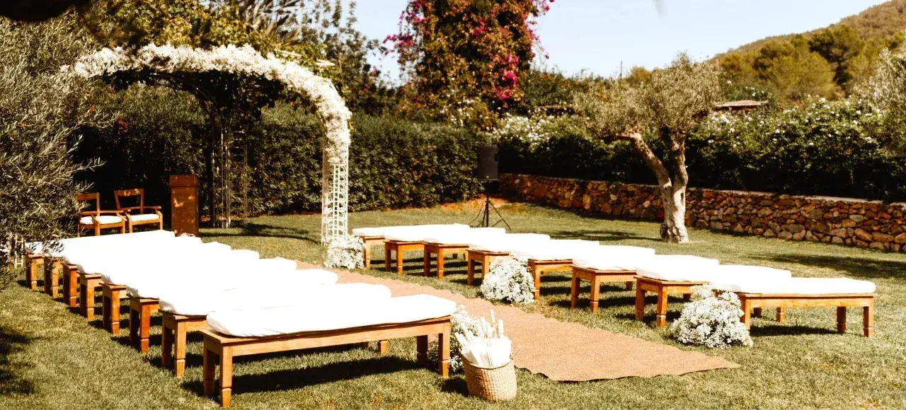Agroturismo Atzaró: Ceremony set-up on a lawn with white benches and a floral arch