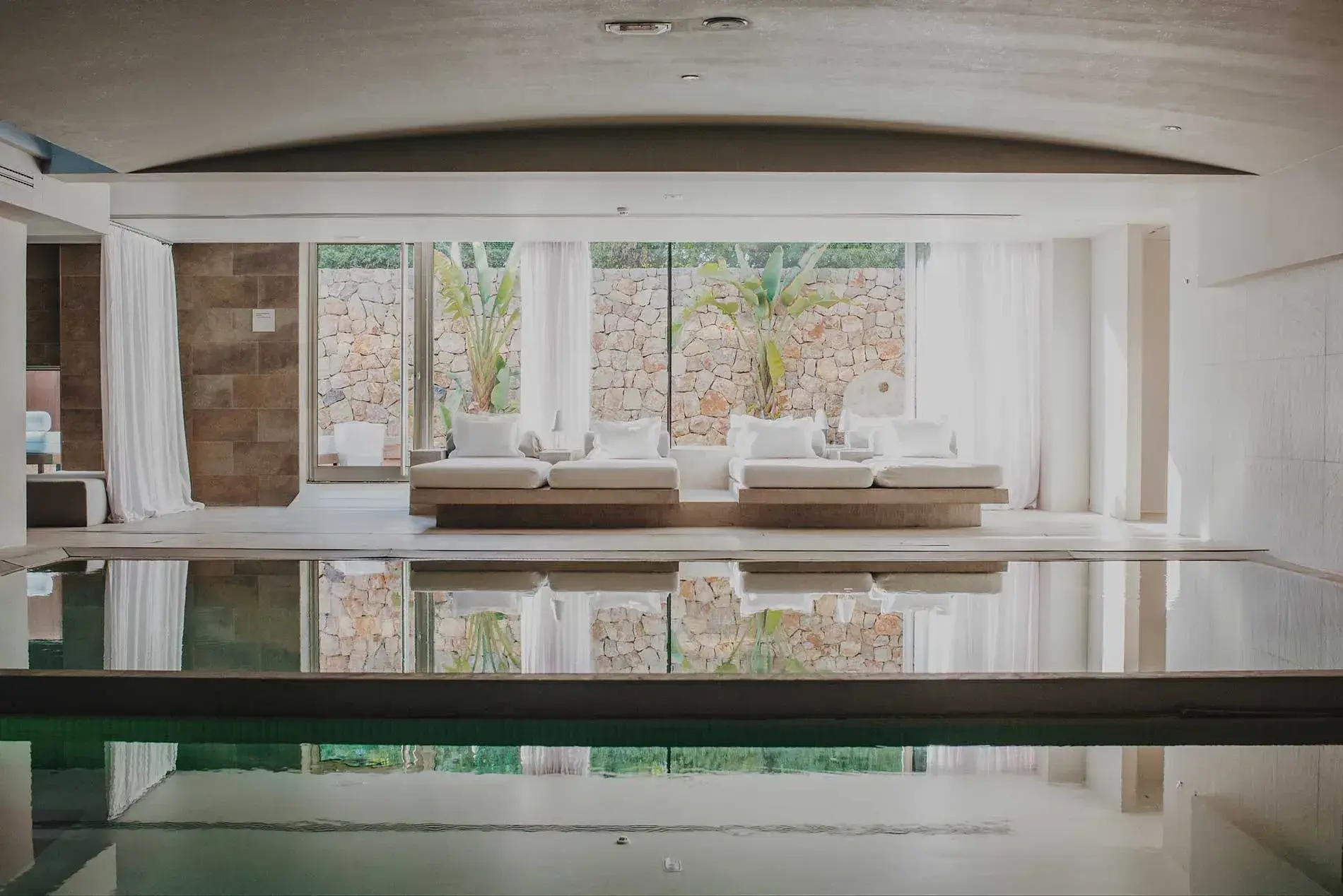 Aguas de Ibiza: Indoor spa pool with white daybeds and a dry-stone garden wall
