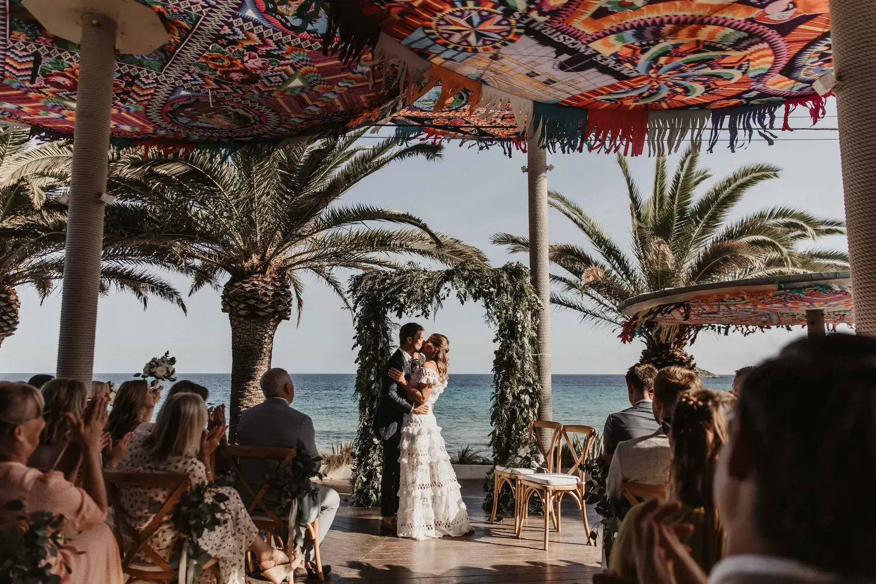 Couple at a boho ceremony arch by the sea at Aiyanna Ibiza
