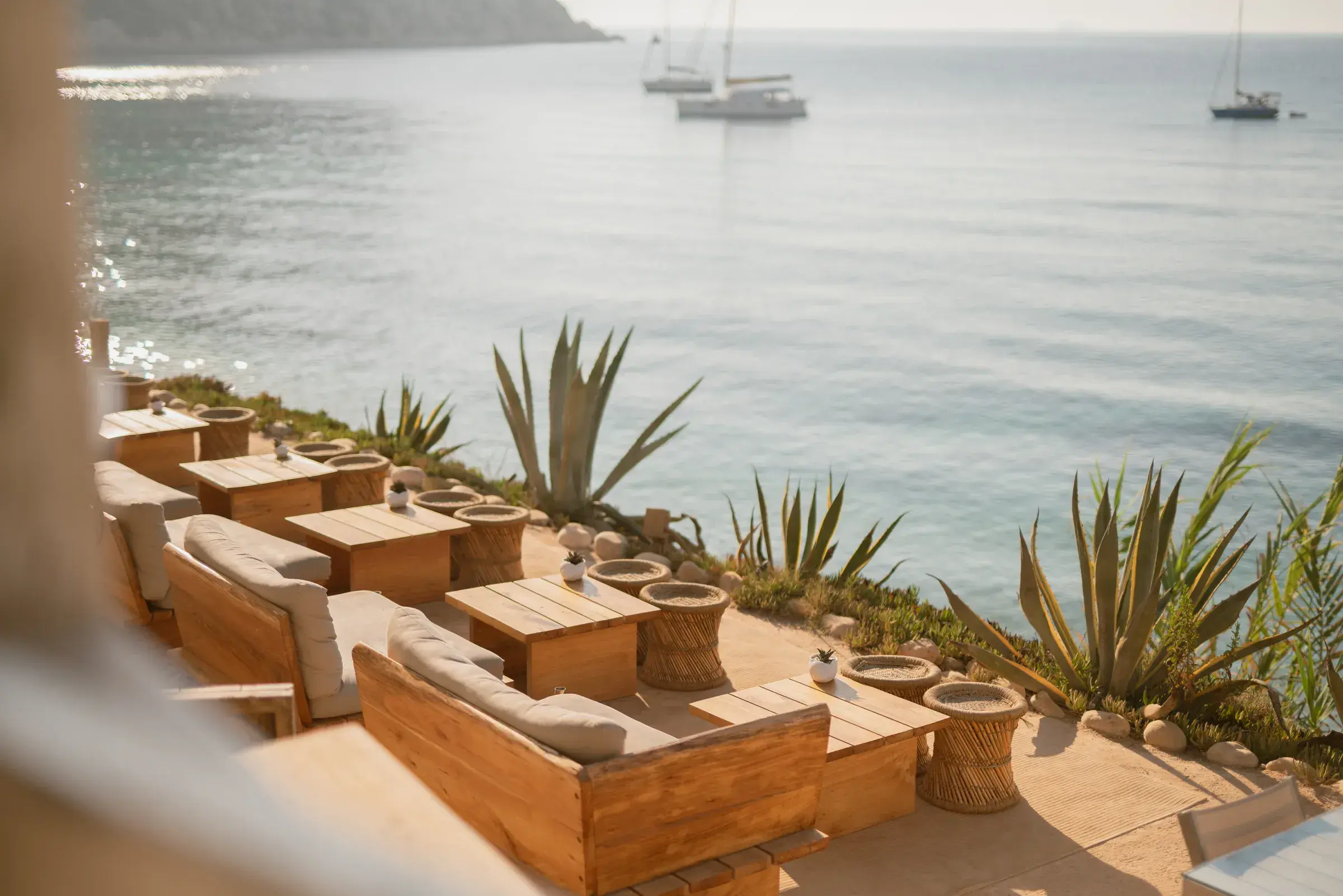 Amante Ibiza: Lounge terrace with wooden sofas and agaves above the bay