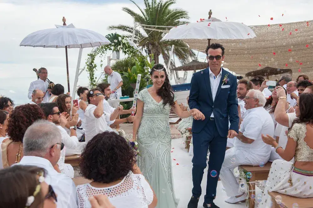 Atzaró Beach: Newly married couple walking back down the aisle between guests under white parasols