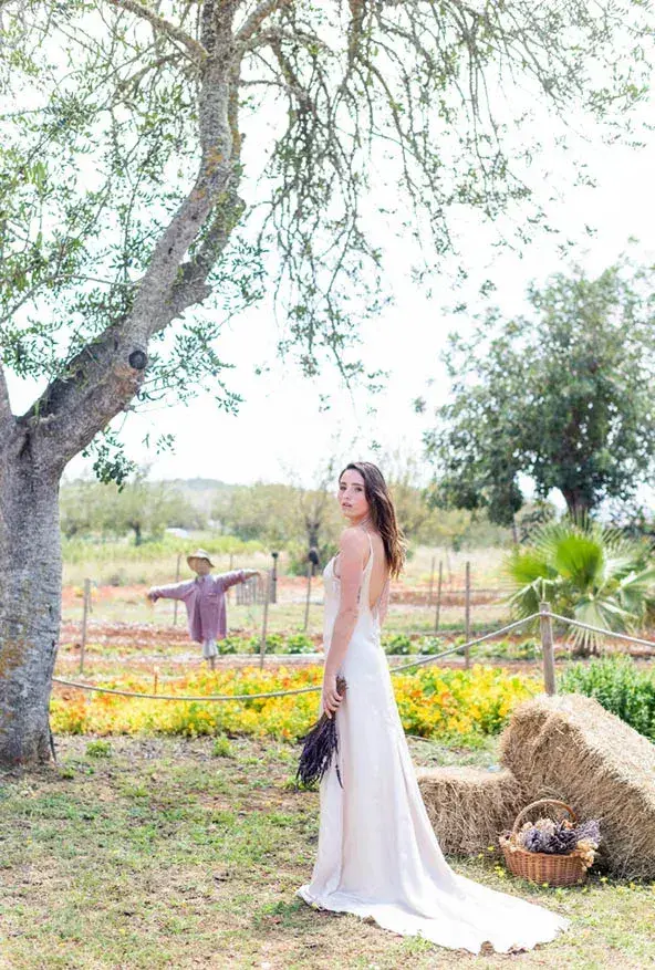 Aubergine by Atzaró: Bride standing in the garden by an olive tree