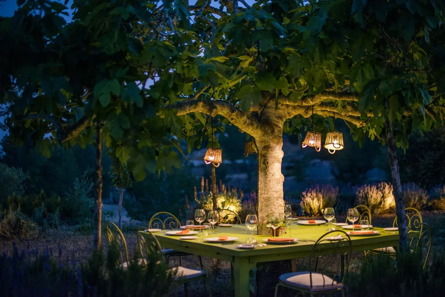 Can Domingo: Tables lit under a large tree in the garden at dusk