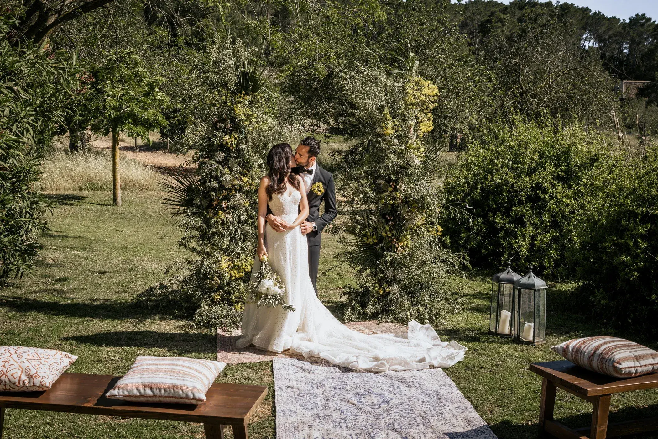 Can Lluc: Bride and groom at a garden ceremony with low wooden benches and cushions
