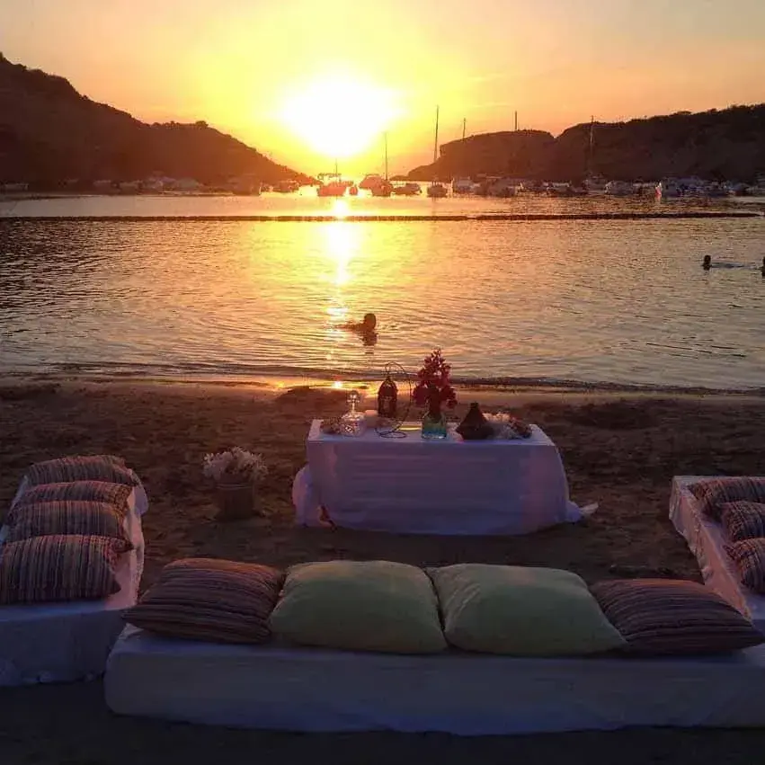 Cana Sofía: Low cushioned seating and a table set on the beach at sunset