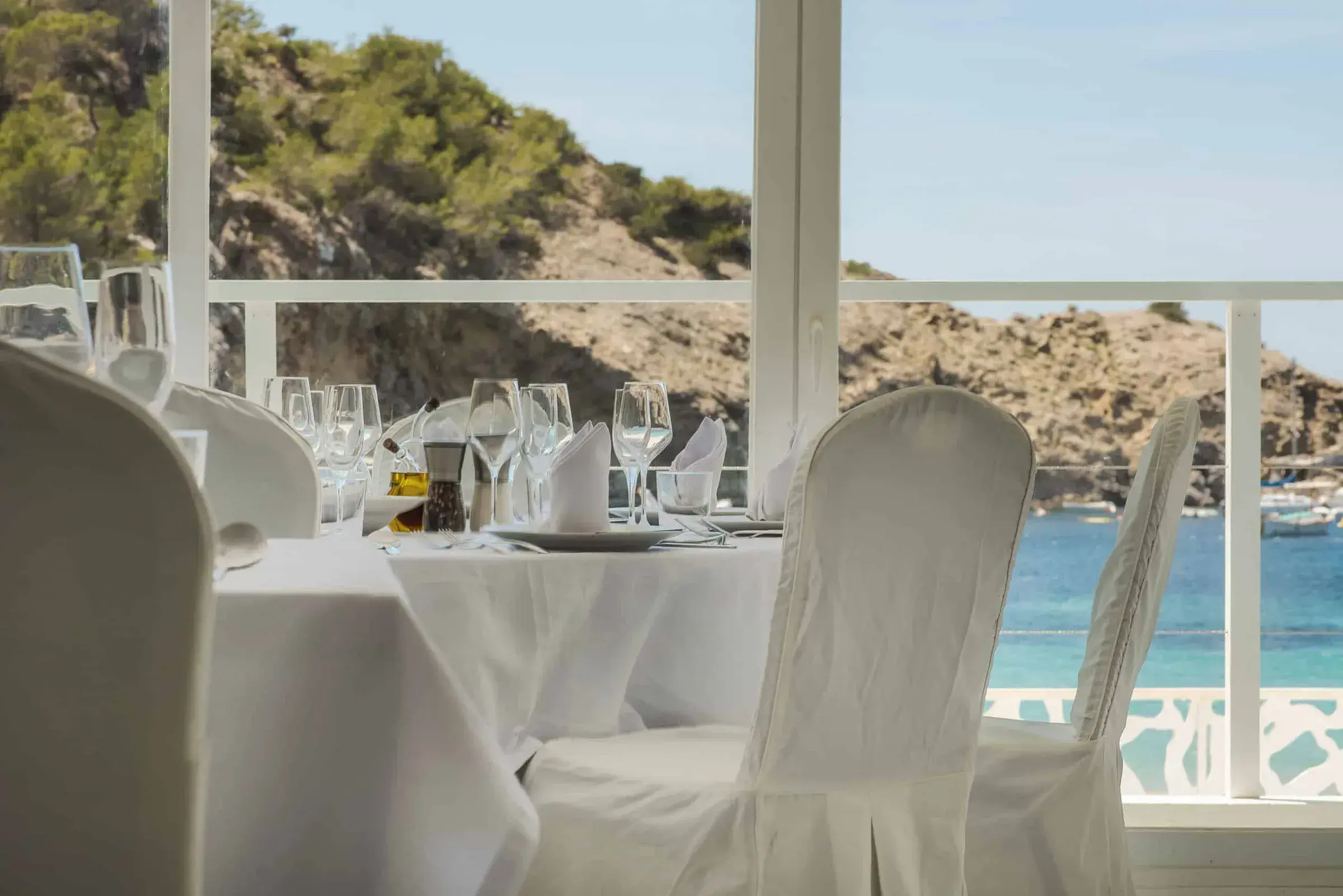 Cana Sofía: Dining room with white-dressed chairs and cove view