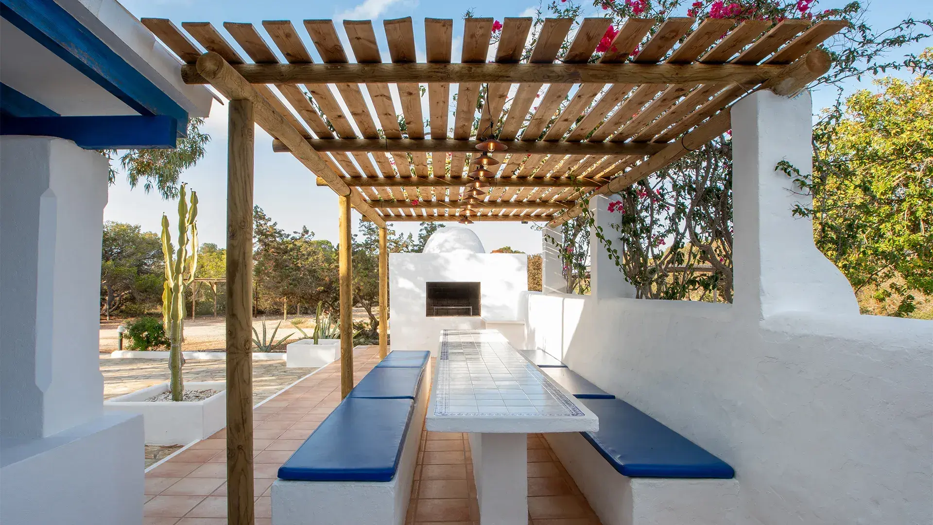 Cantoniblay: Pergola dining table with blue cushions and outdoor oven