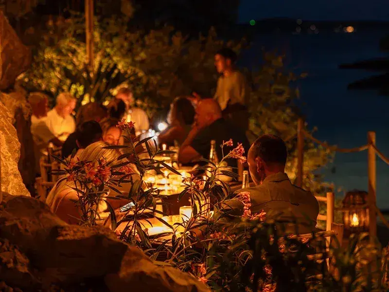 El Chiringuito Cala Gracioneta: Guests dining by candlelight among the rocks at night, from the venue's weddings and events section (800px)
