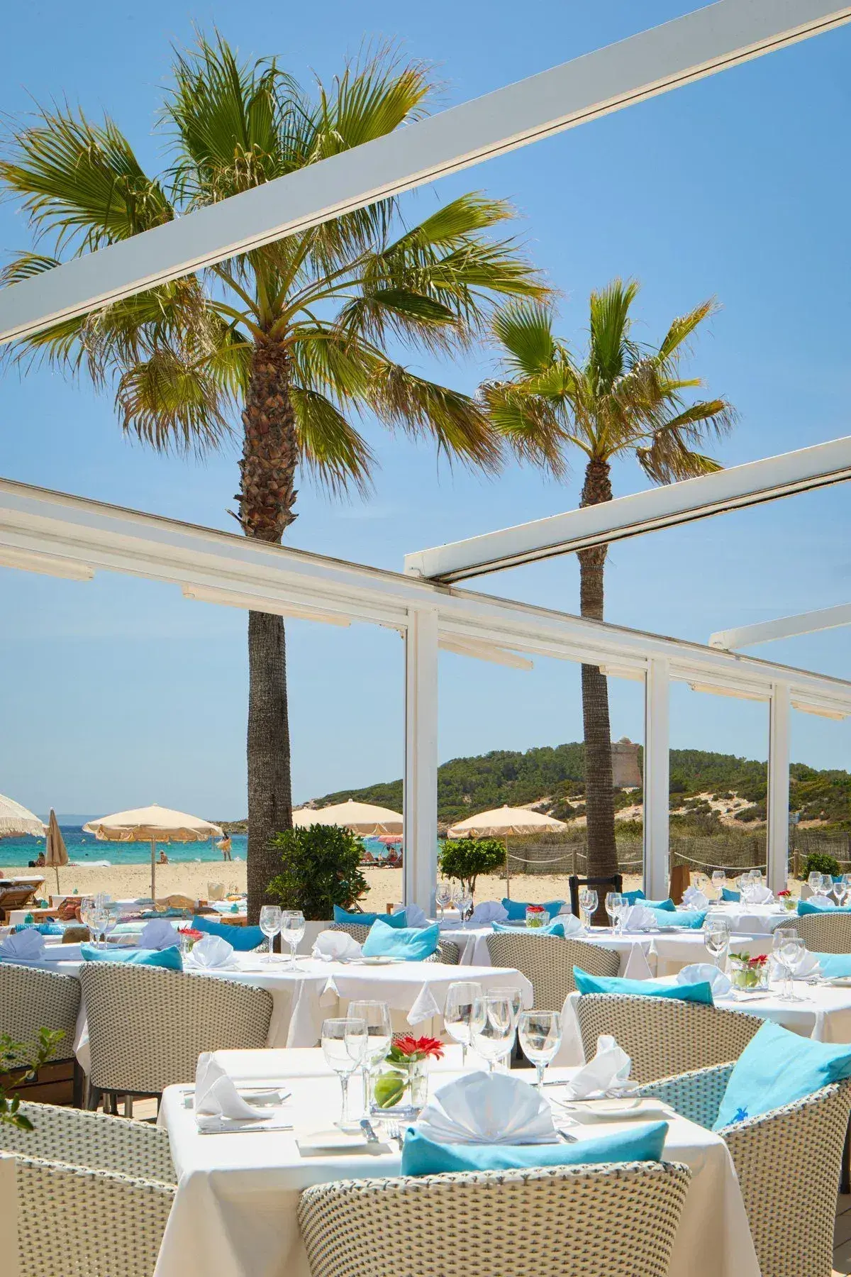Coco Beach Ibiza: Restaurant terrace tables under palm trees with the beach behind