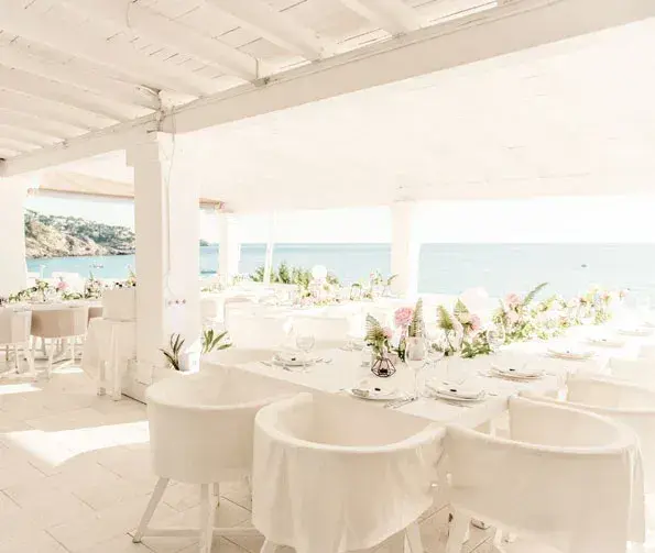Cotton Beach Club: Terrace dressed for an event dinner with white tablecloths and flower arrangements, sea beyond (595px wide)