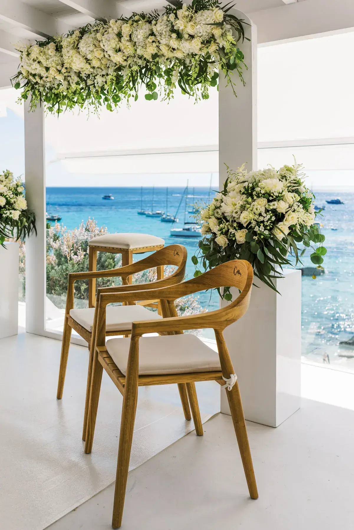 Ceremony set-up with white flowers and the sea at Cotton Beach Club