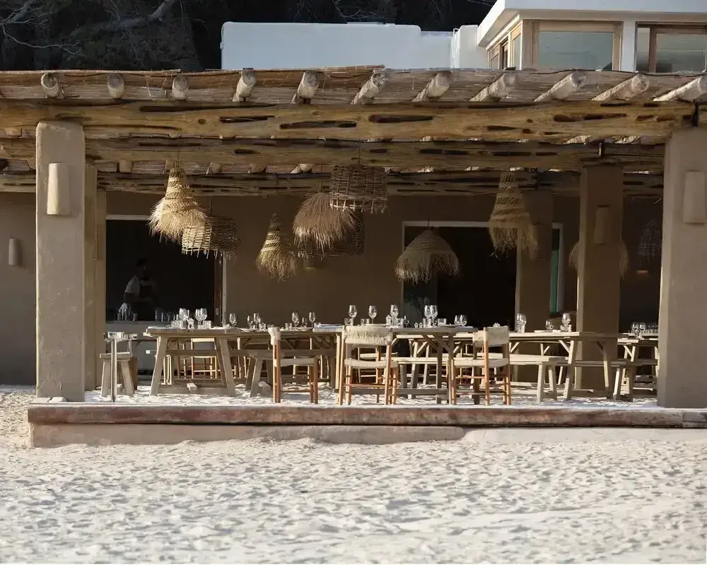 El Silencio: Beach restaurant terrace with rattan lamps and long tables set on the sand