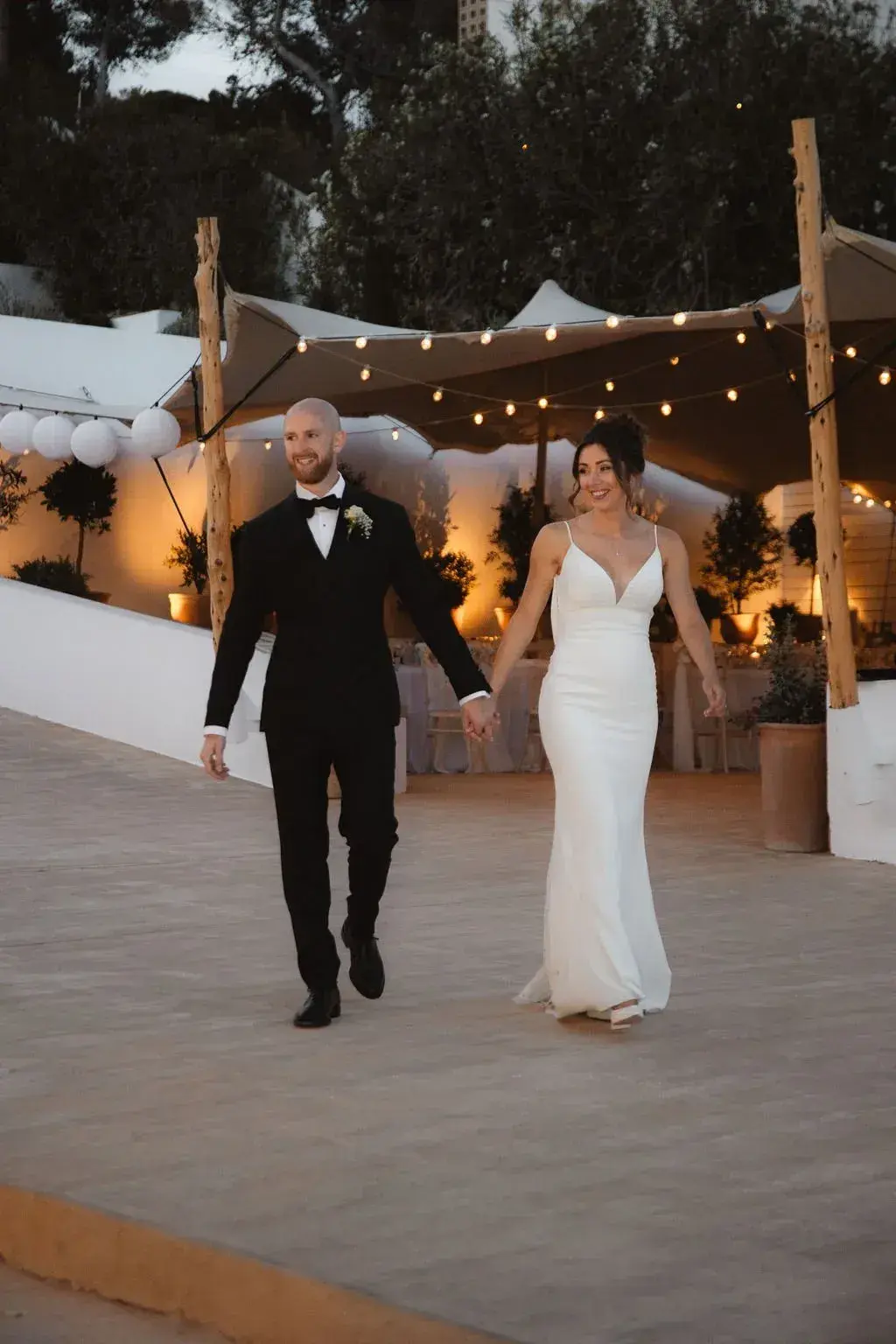 Elixir: Couple walking out of the festoon-lit dinner area in the evening