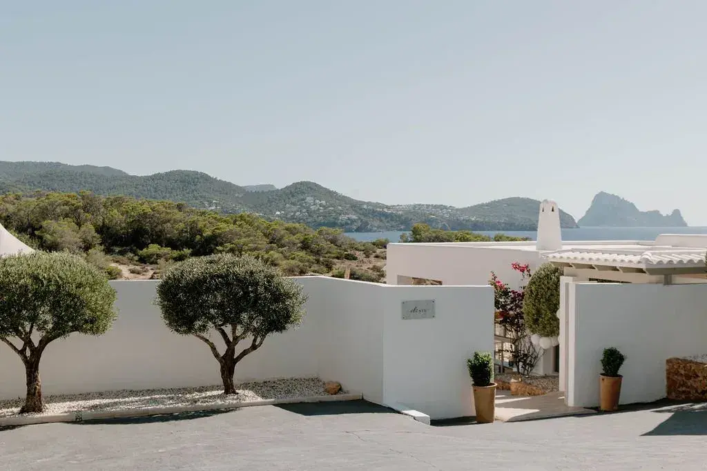 Elixir: White venue buildings and olive trees with Es Vedrà on the horizon