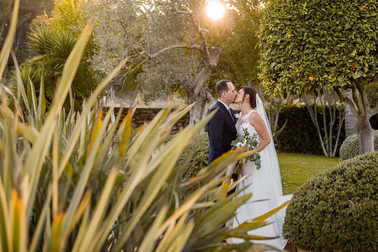 Es Jardins de Fruitera: Bride and groom kissing in the garden among plants at dusk