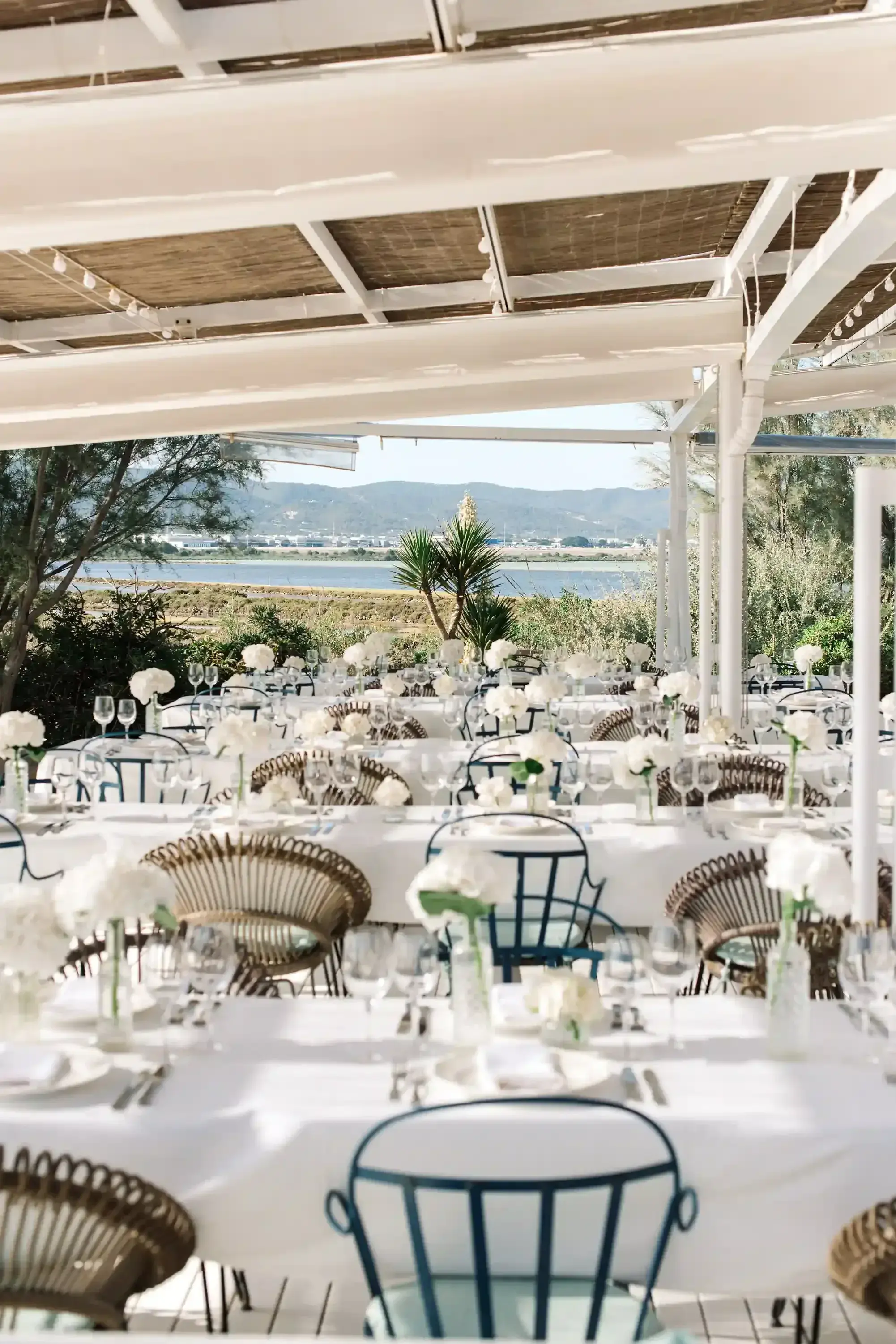 Experimental Beach: Restaurant terrace dressed for an event dinner with white tablecloths and white floral centrepieces
