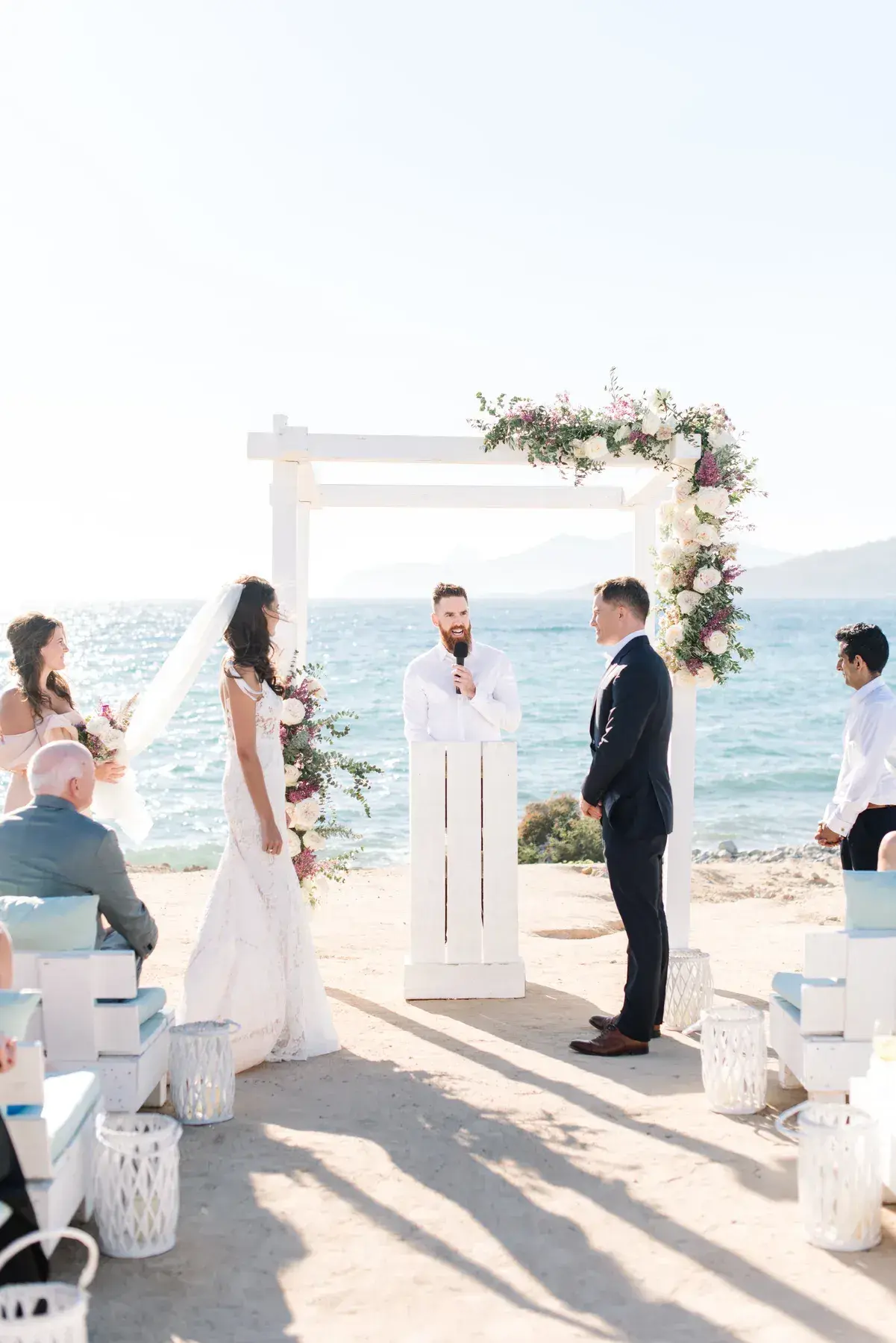 Beach wedding ceremony at a white flower arch by the sea at Experimental Beach