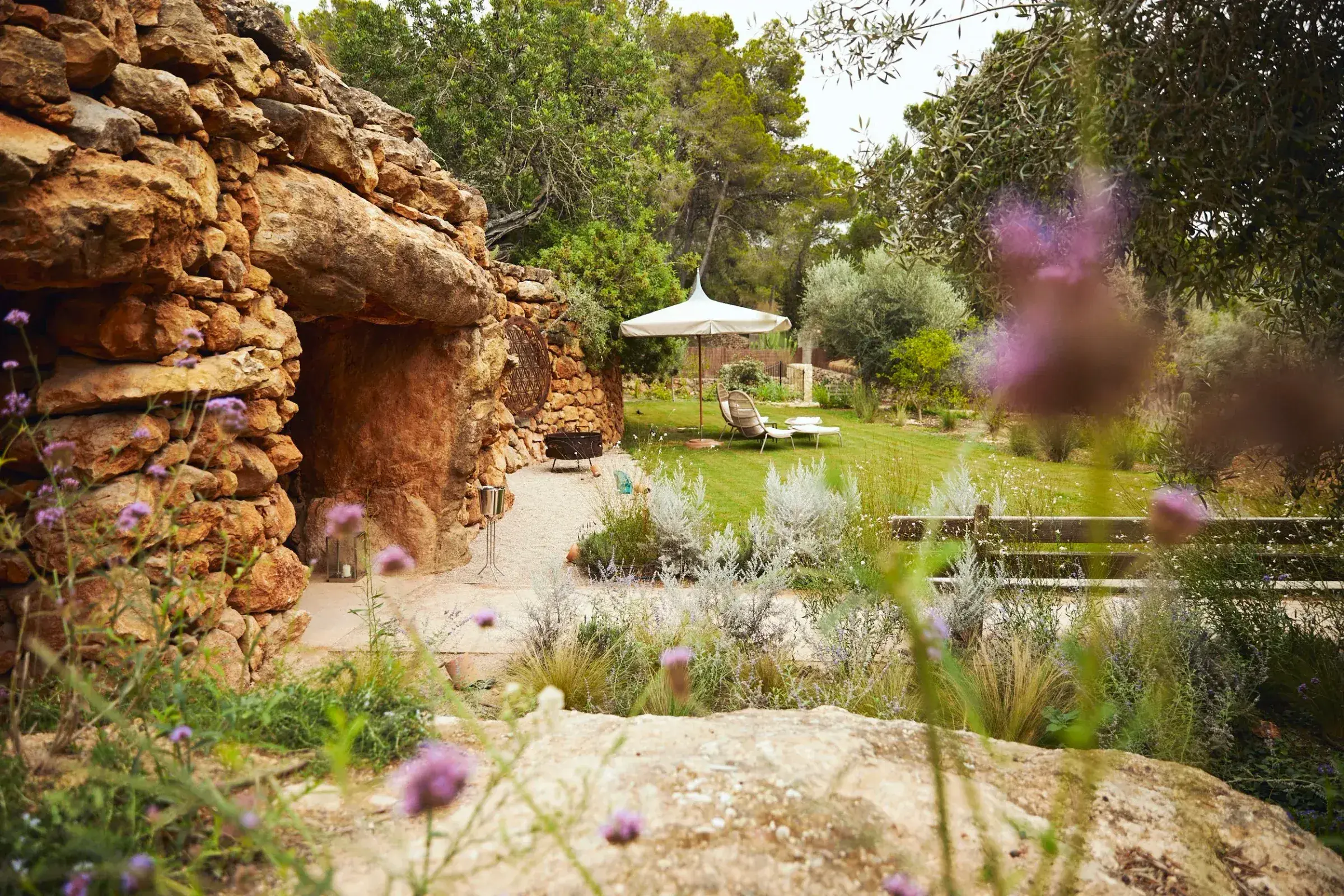 Fincadelica San Lorenzo: Garden with dry-stone cave, lawn and parasol among olive trees