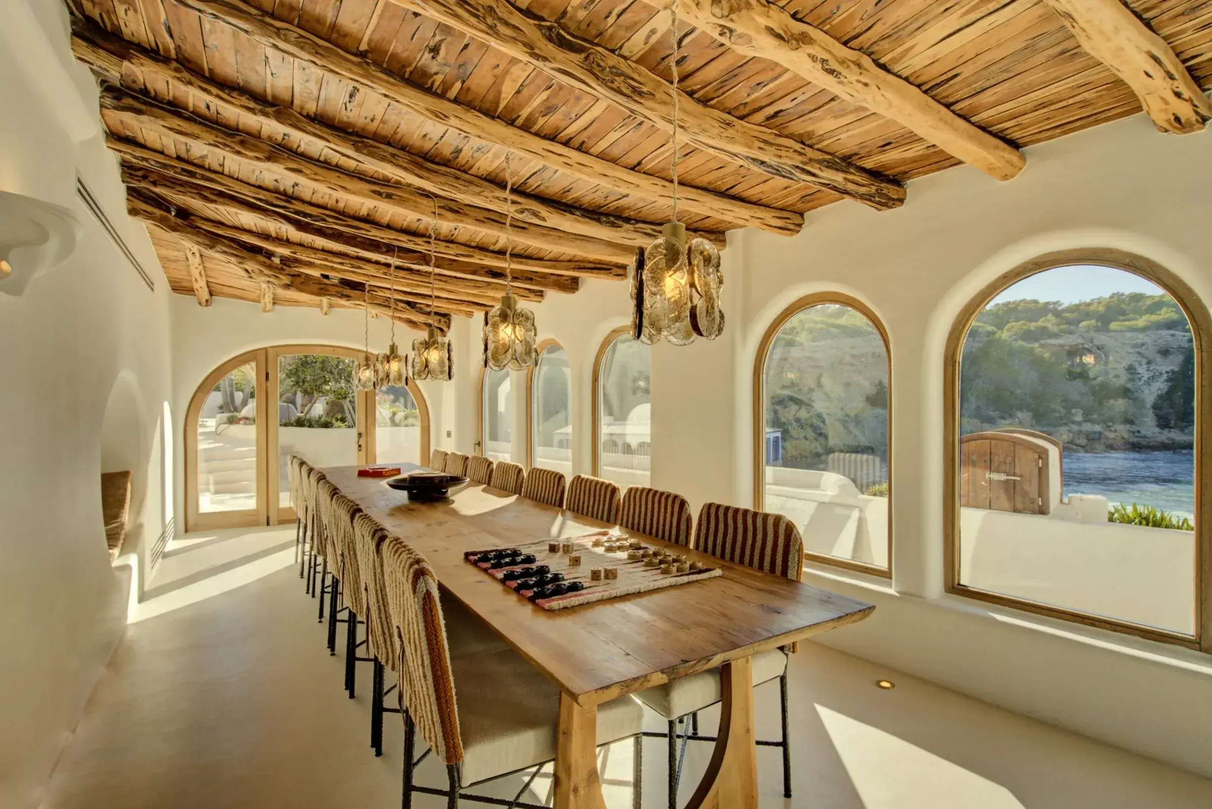 Fincadelica Xarraca: Dining room with long table, beamed ceiling and arched sea-view windows