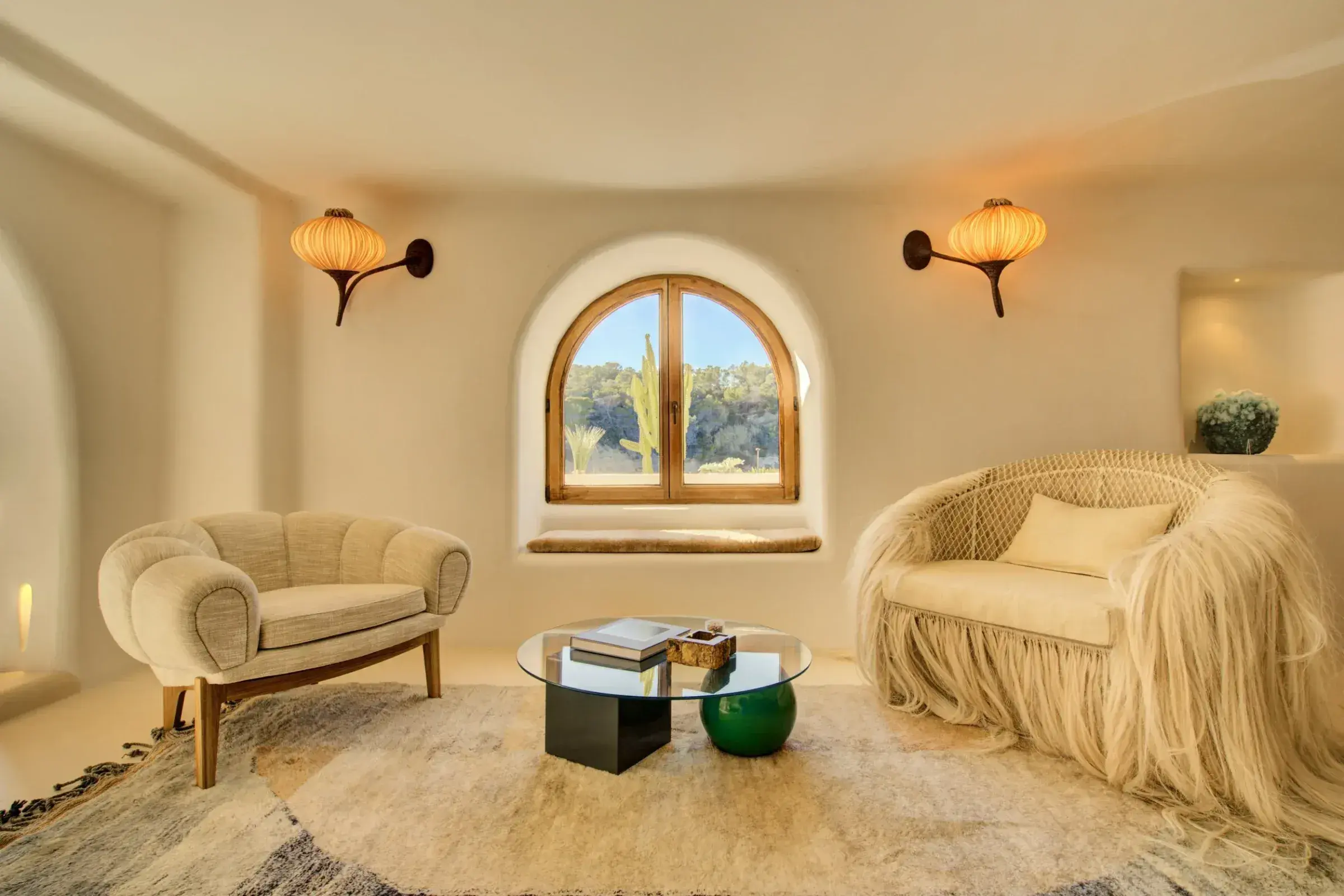 Fincadelica Xarraca: Sitting room with arched window and sculptural armchairs