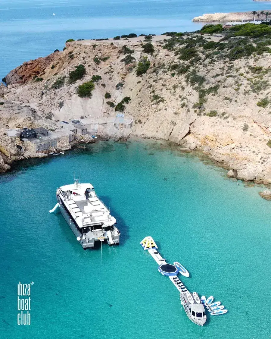 Ibiza Boat Club: Aerial view of the catamaran in a cove below cliffs