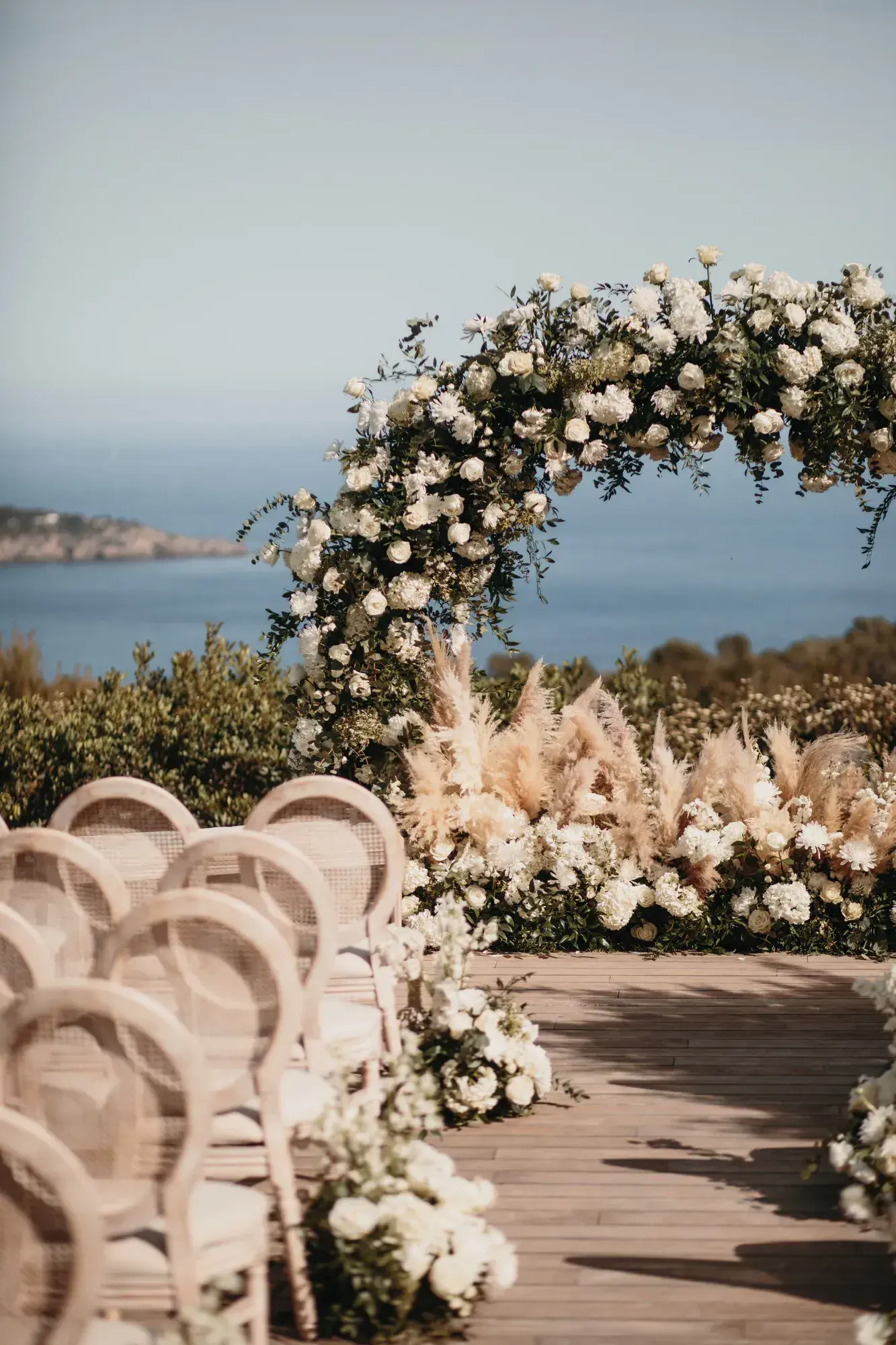 An arch of white flowers and pampas above the sea