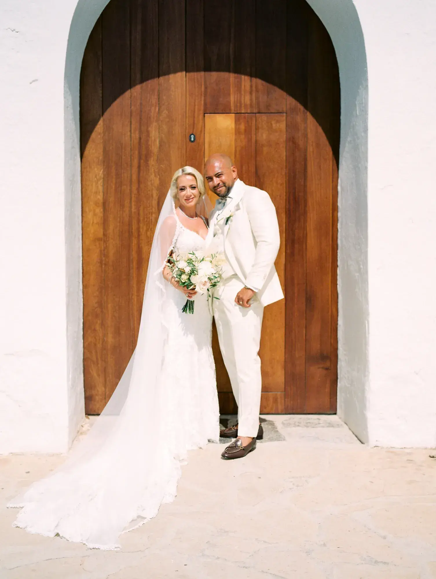 Bride and groom at an arched wooden door, ME Ibiza