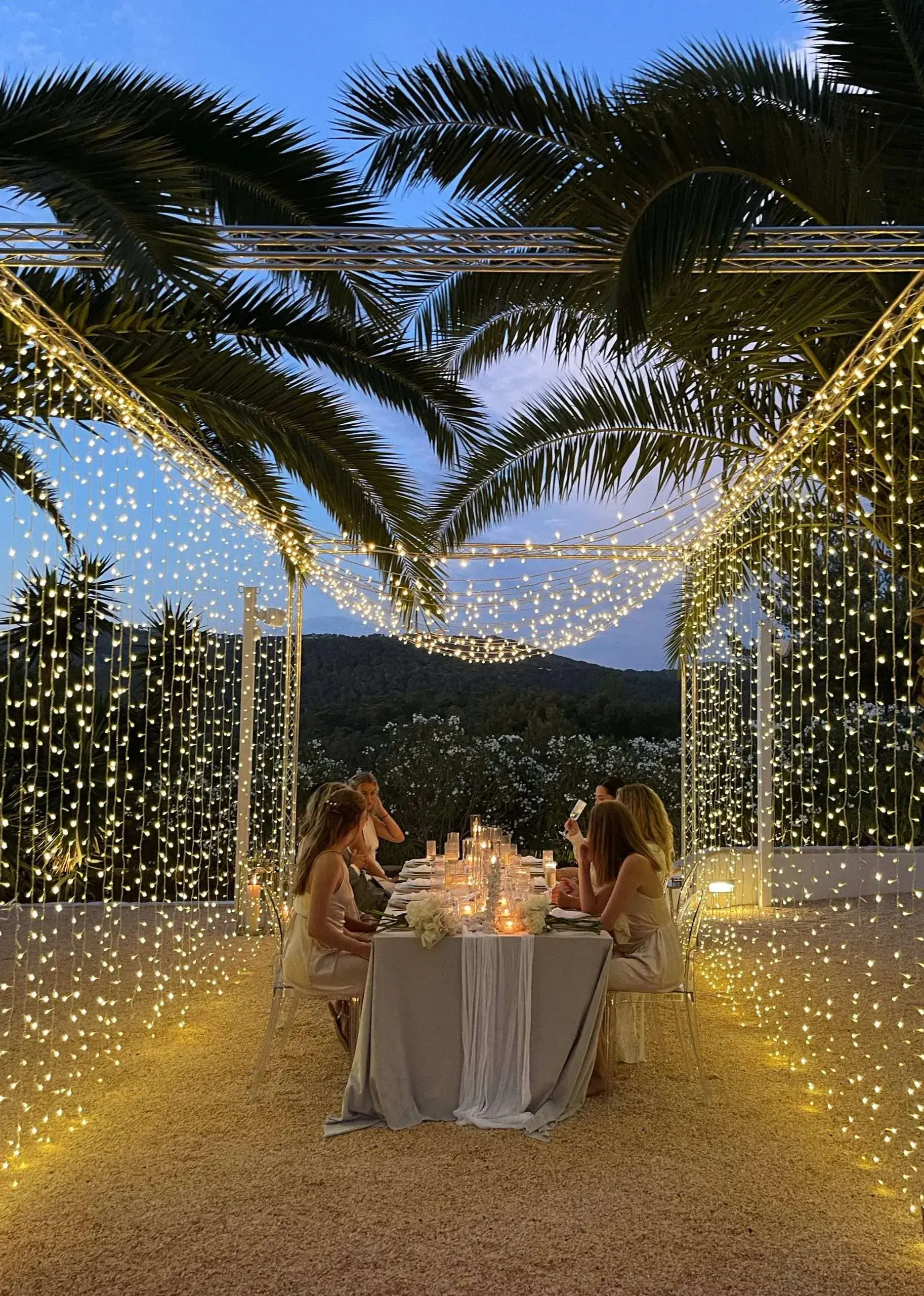 Kazamor: Small dinner table inside a curtain of fairy lights at dusk