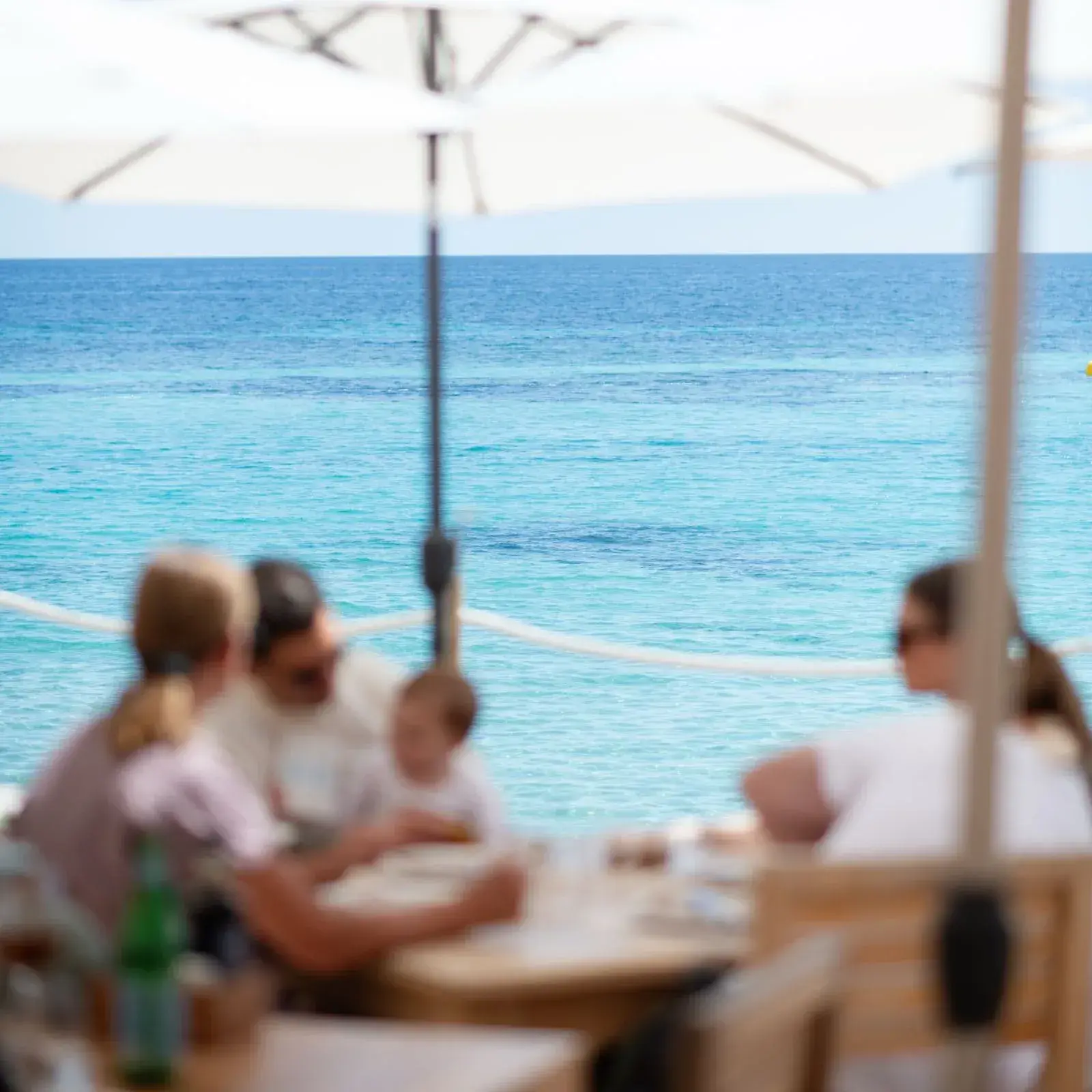La Escollera: Diners on the terrace under parasols with the turquoise sea behind
