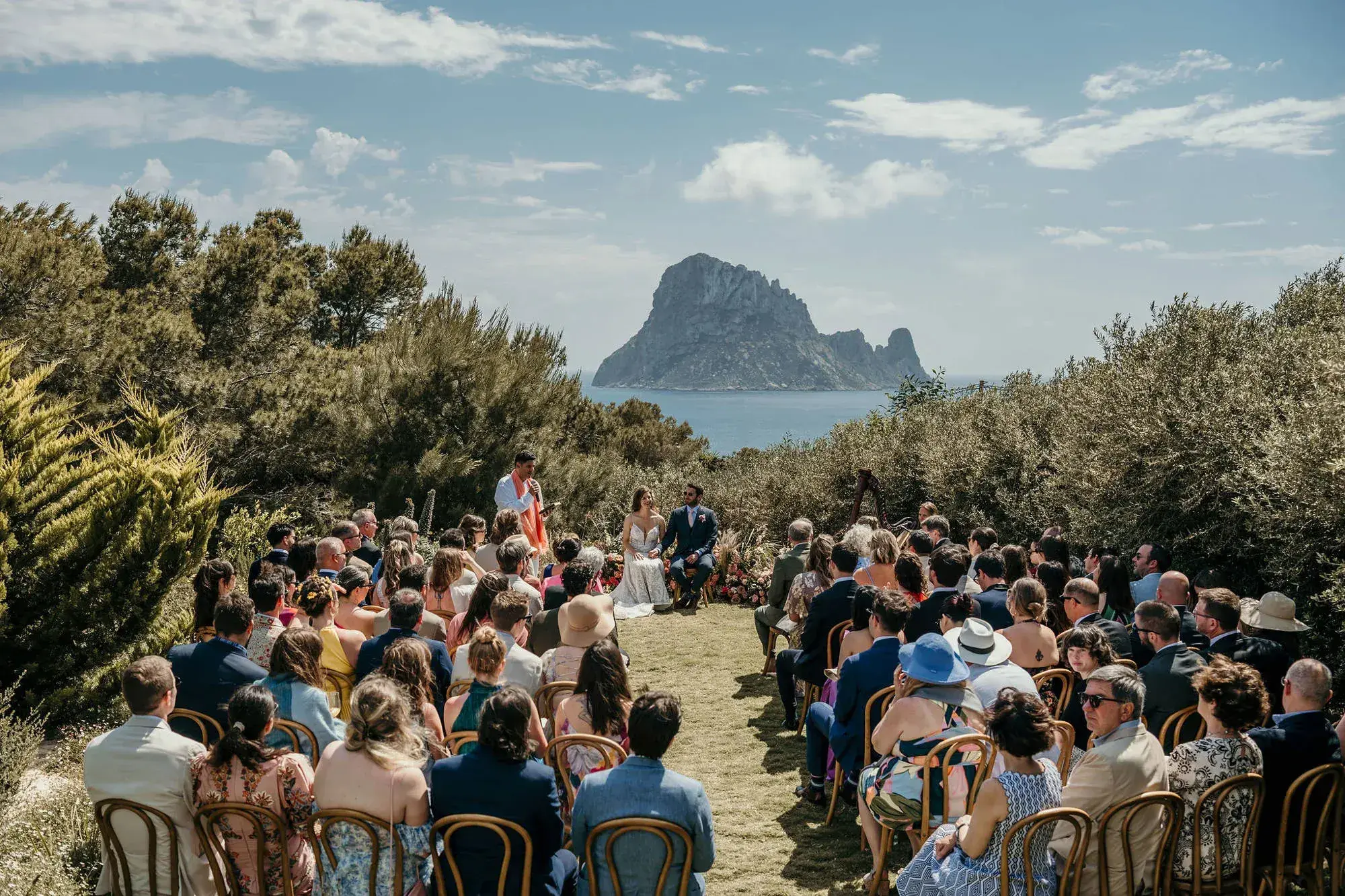 Petunia Ibiza: Guests seated for a garden ceremony with Es Vedrà in the distance