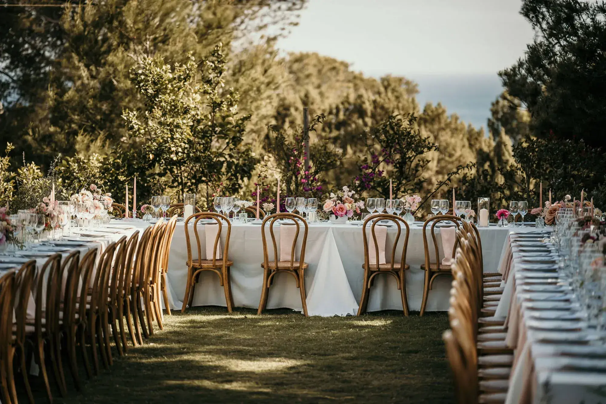 Petunia Ibiza: Long dinner tables with wooden chairs laid out on the garden lawn