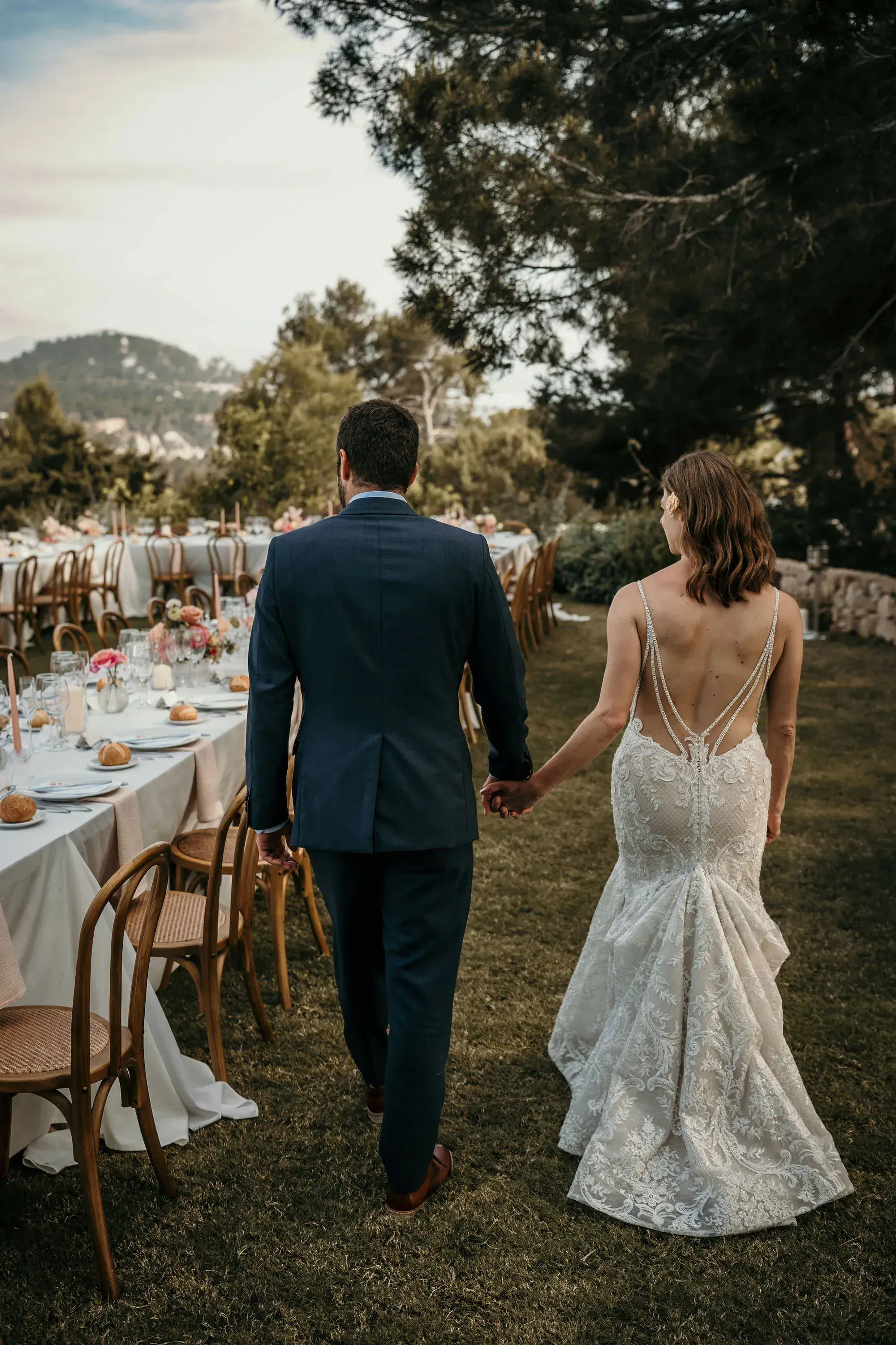 Petunia Ibiza: Bride and groom walking past the set dinner tables in the garden