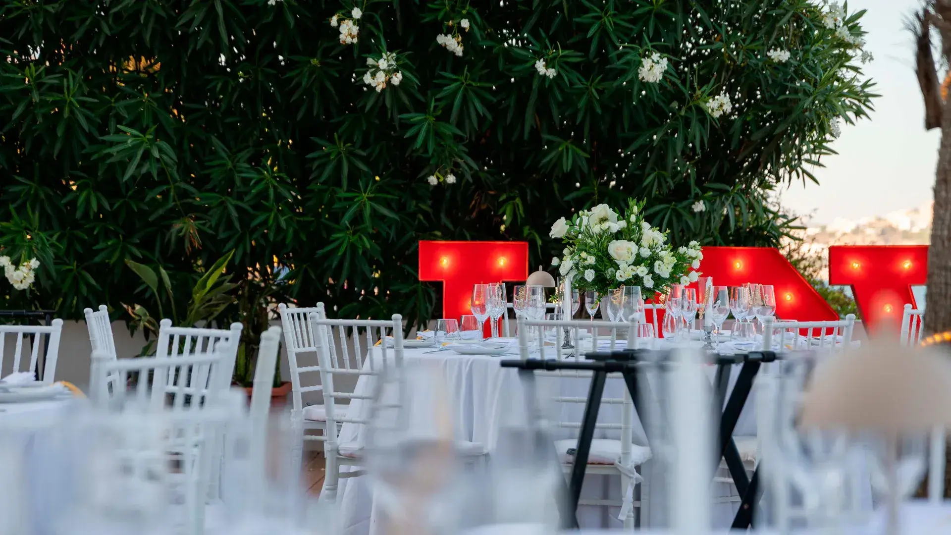 Seahorse Beach Club: Garden dressed for an evening event dinner with white chairs, flowers and light-up letters