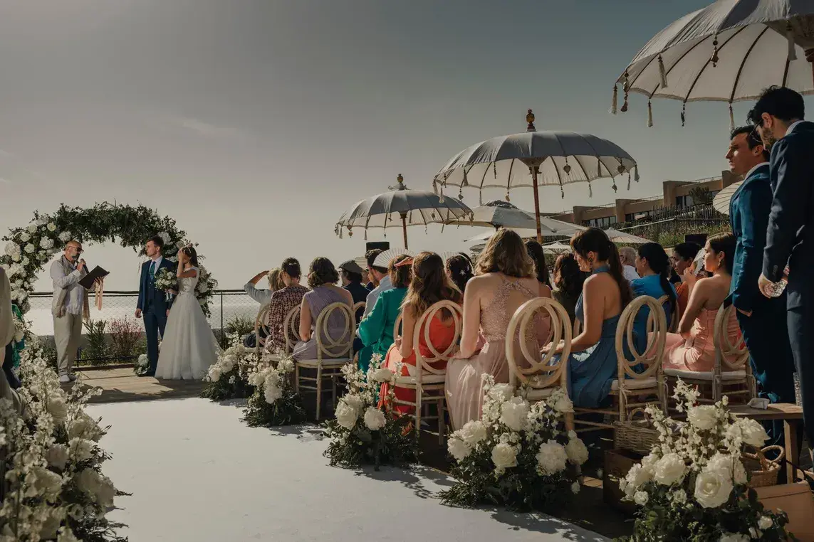 Six Senses Ibiza: Ceremony under parasols on the clifftop lawn with guests seated along a flower-lined aisle