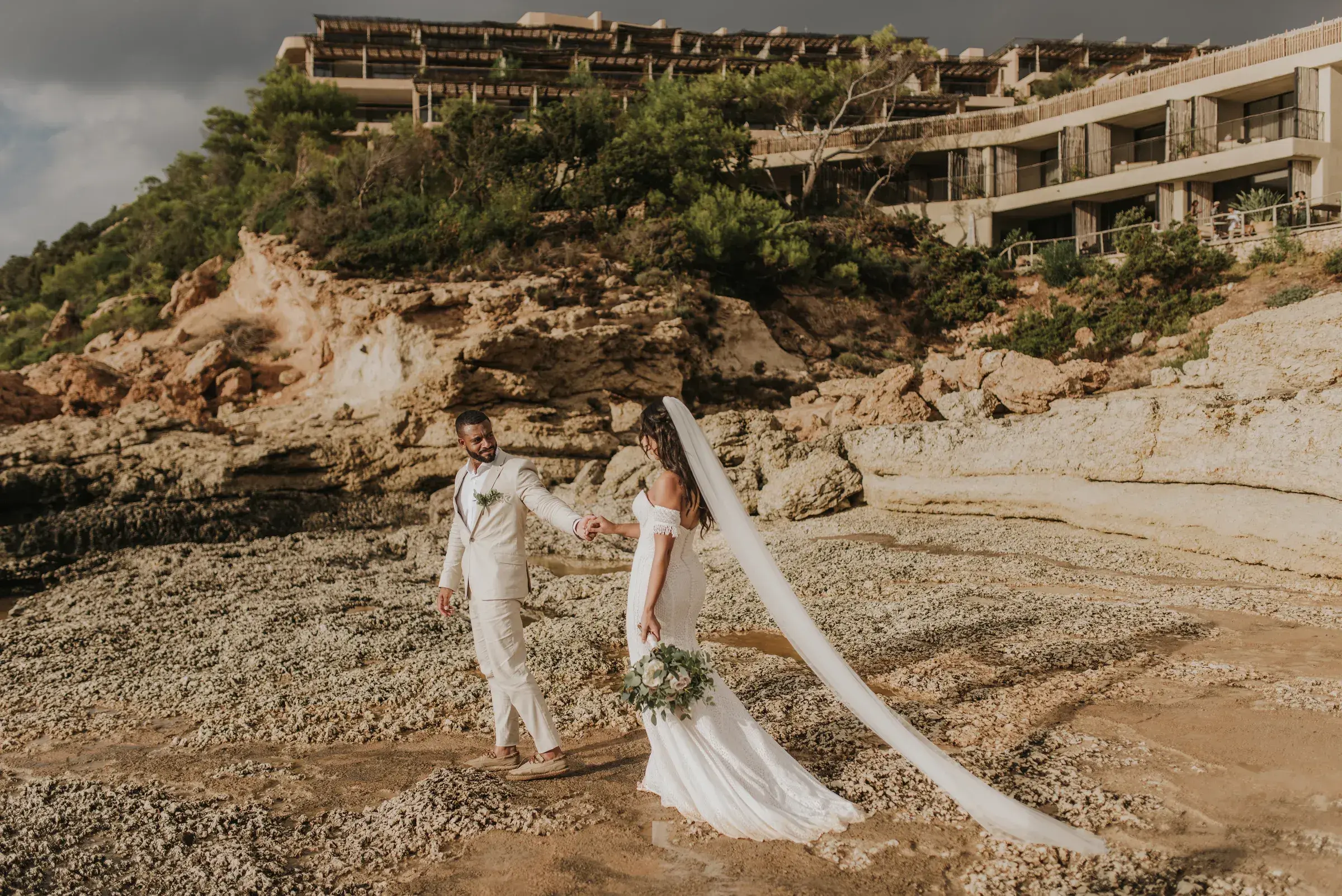 Six Senses Ibiza: Couple on the rocky shore below the resort buildings