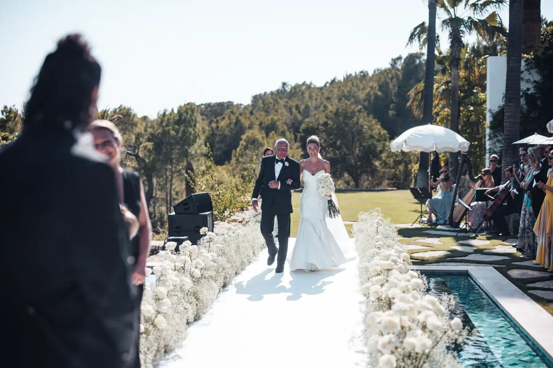 Bride walking down a white aisle lined with flowers at Villa Bliss Palm