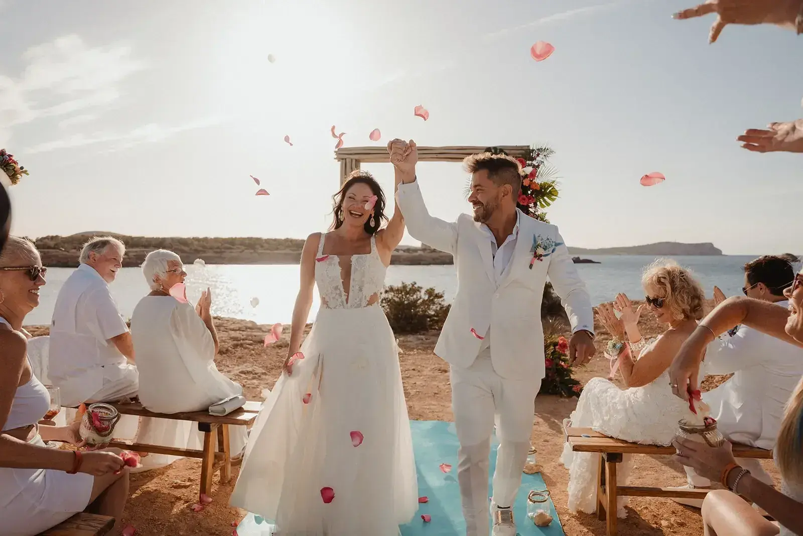Cala Bassa Beach Club: Bride and groom celebrating after a beach ceremony as guests throw petals