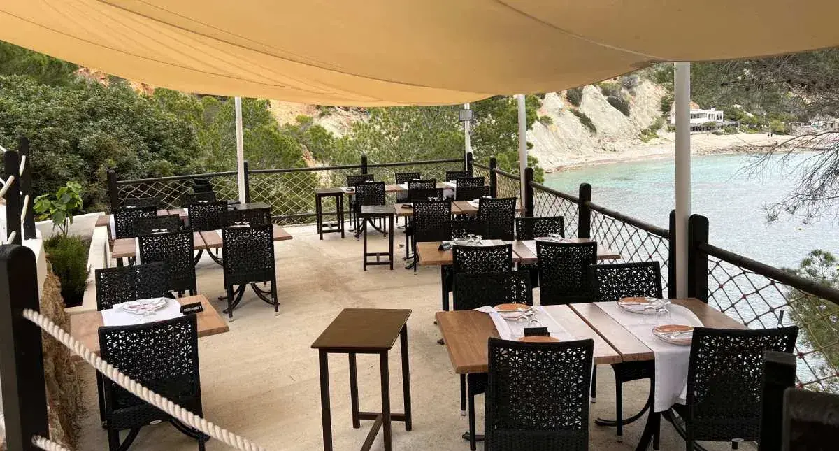 Es Boldado: Terrace dining area under a shade sail above the beach