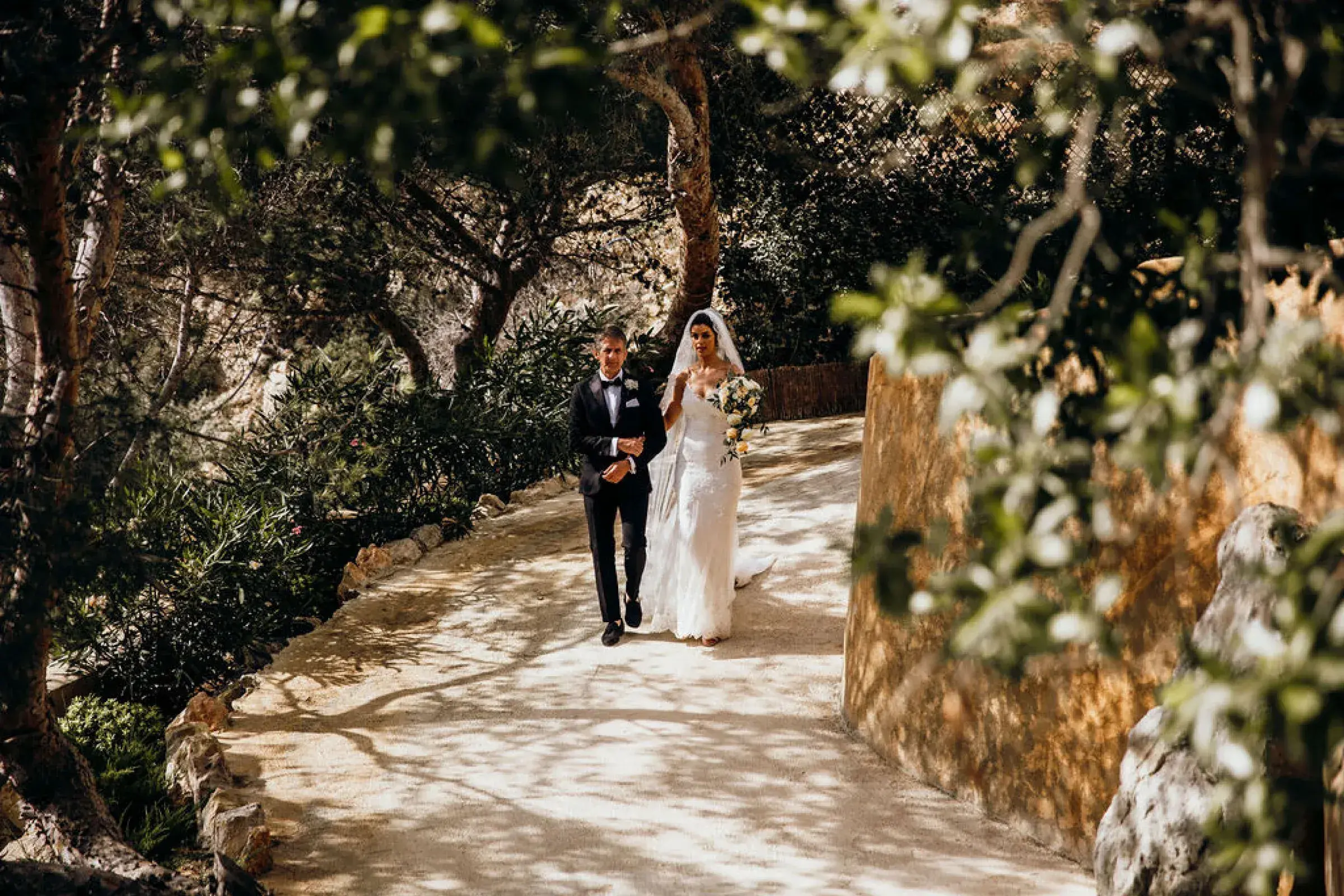 Hacienda Na Xamena: Bride and groom walking down the stone path to the amphitheatre