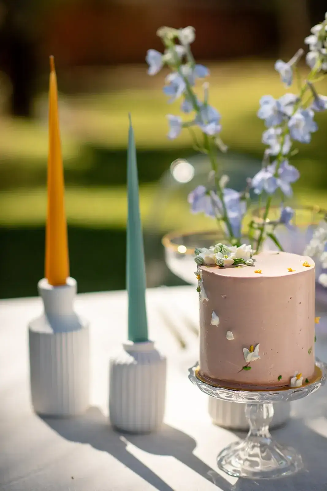 Coloured taper candles beside a small cake, spring styled shoot