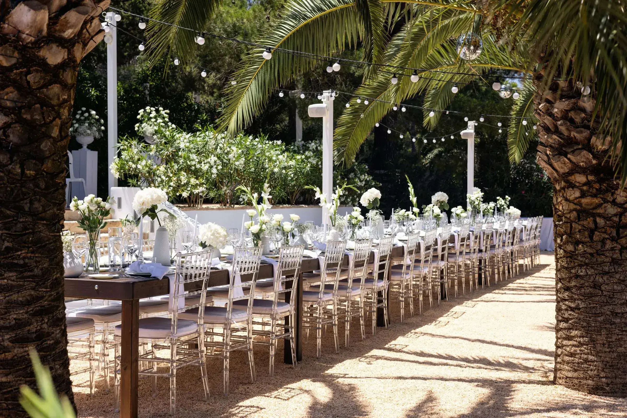 Kazamor: Long banquet table along the palm-lined terrace with festoon lights