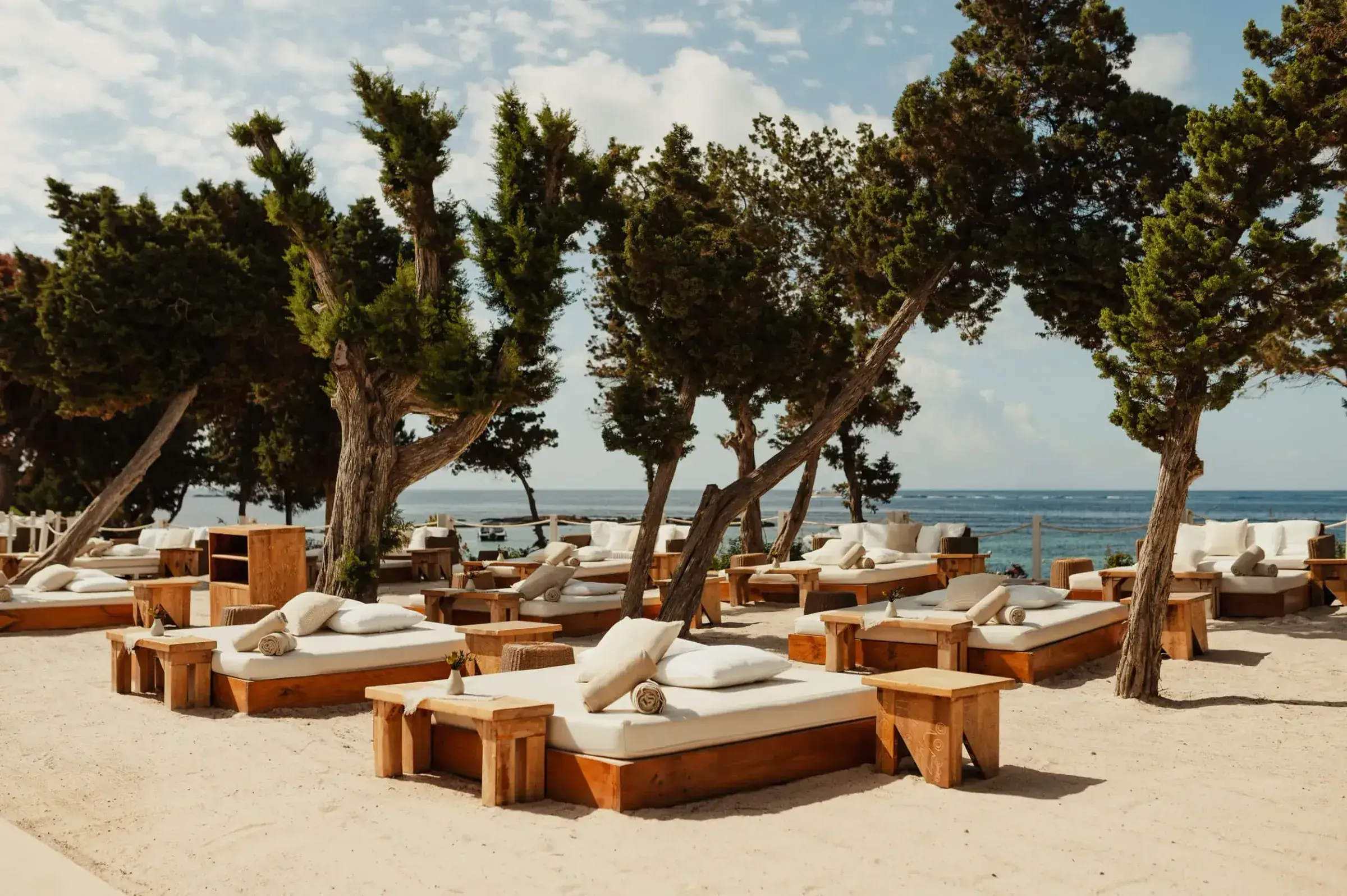 Nikki Beach Ibiza: Beach area with white daybeds under pine trees by the sea