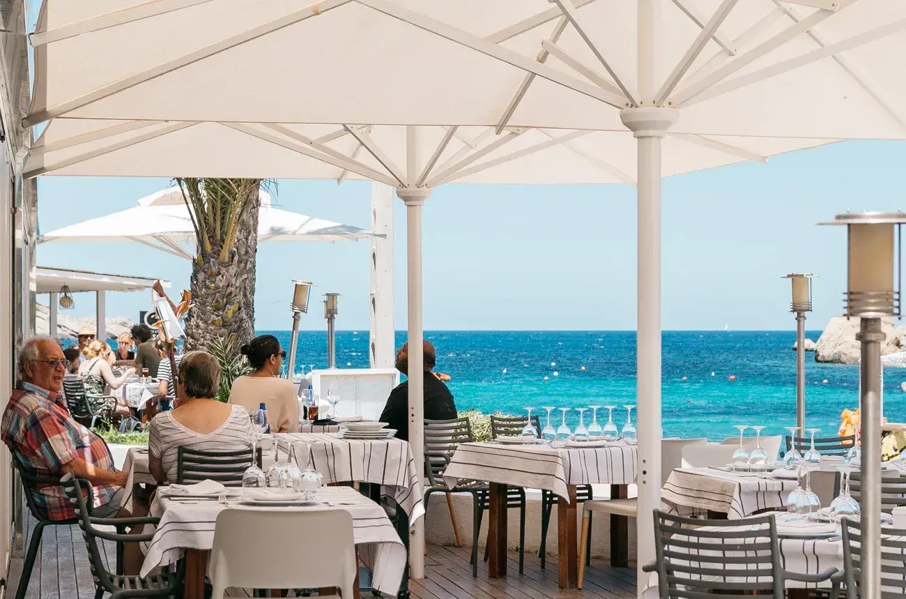 Port Balansat: Seafront terrace with diners and the turquoise bay beyond